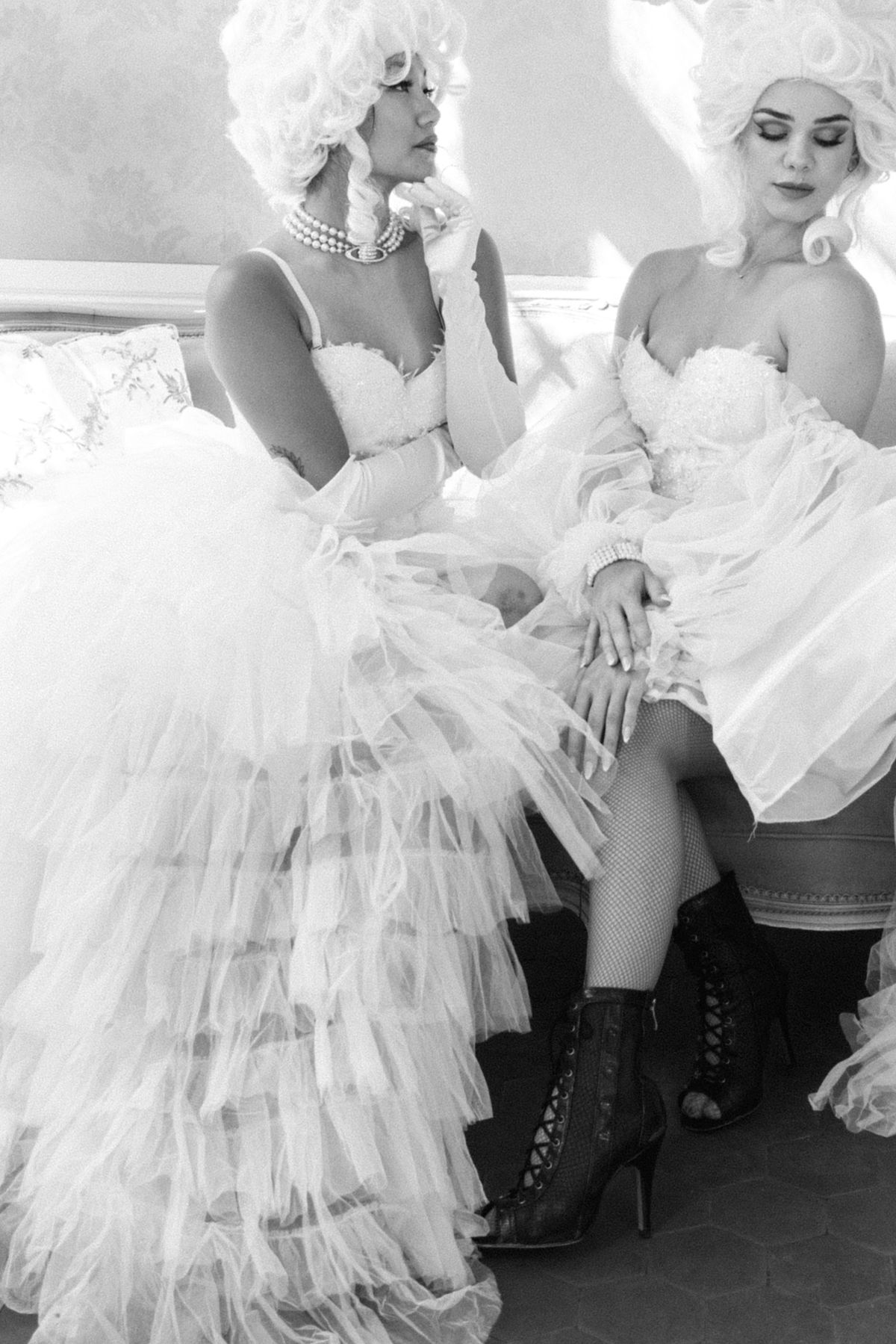 Two costumed performers in powdered wigs and ruffled tulle, in black and white