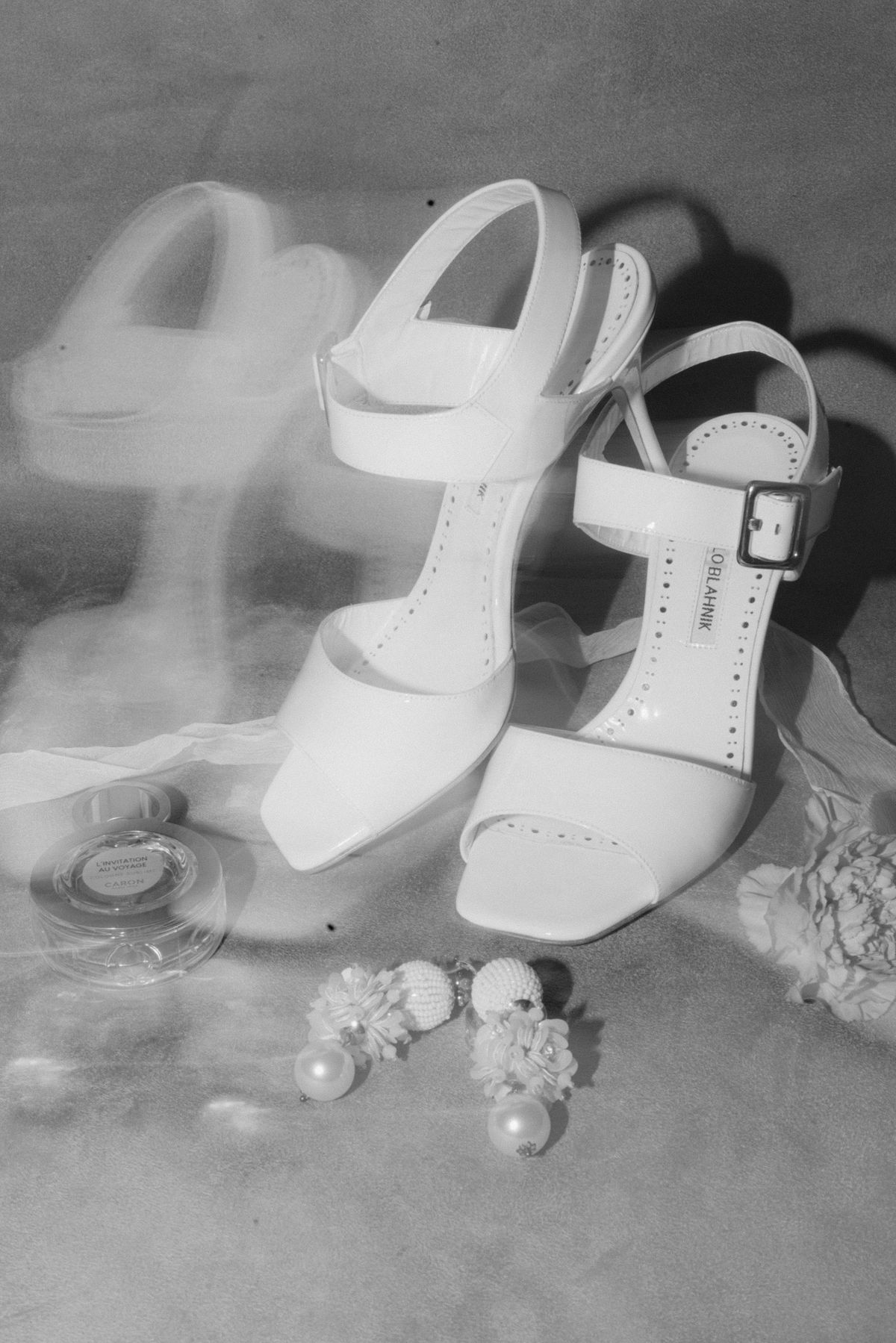 Black and white flat lay of bridal shoes and pearl drop earrings
