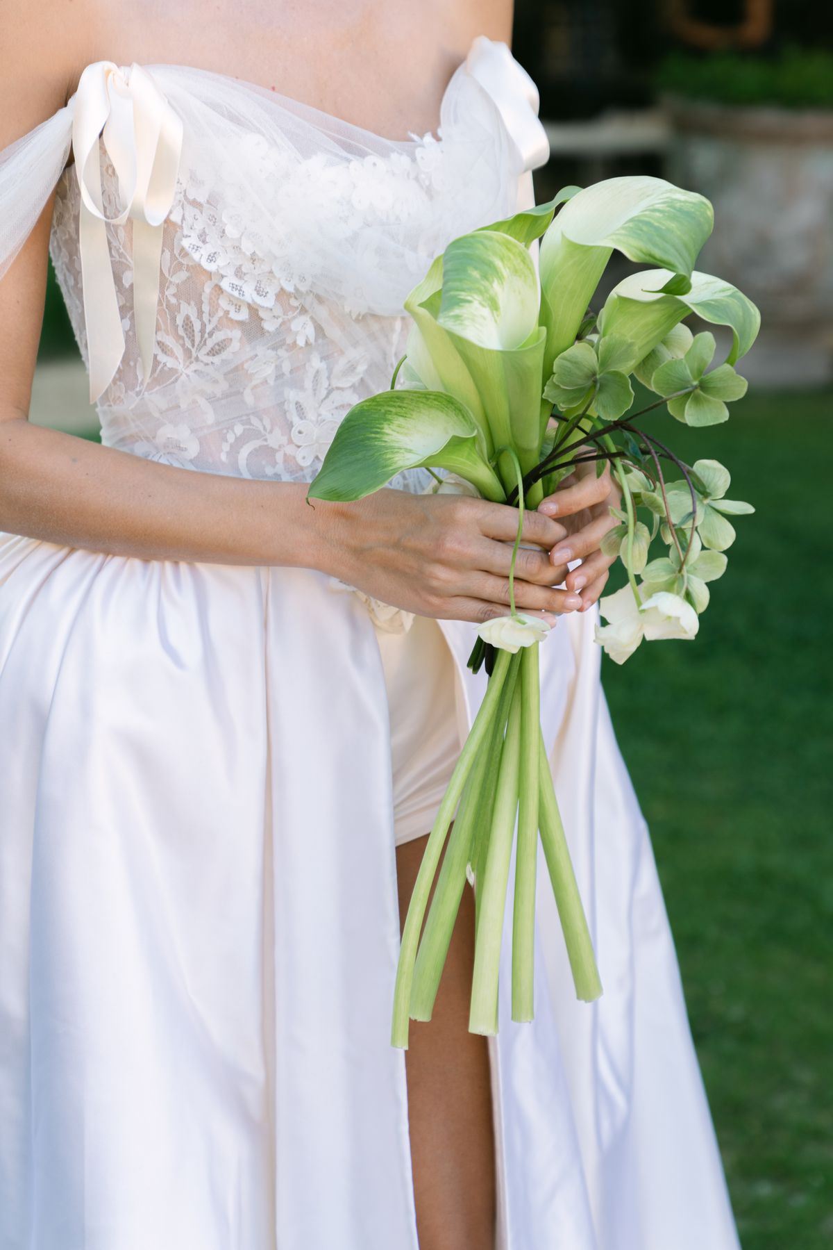 Close view of a calla lily bouquet held against a satin gown bodice