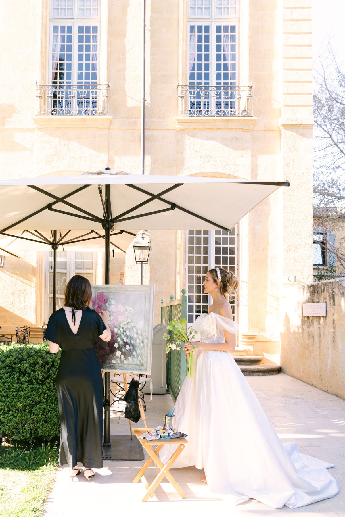 Bride watching a live painter working at an easel outside the building
