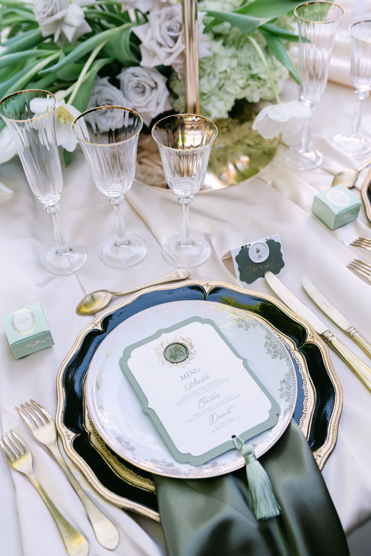 Place setting with a navy and gold charger, printed menu and green tassel