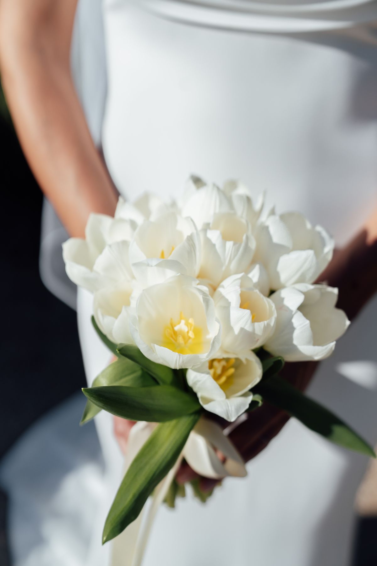 Close view of a white tulip bouquet held against a satin gown