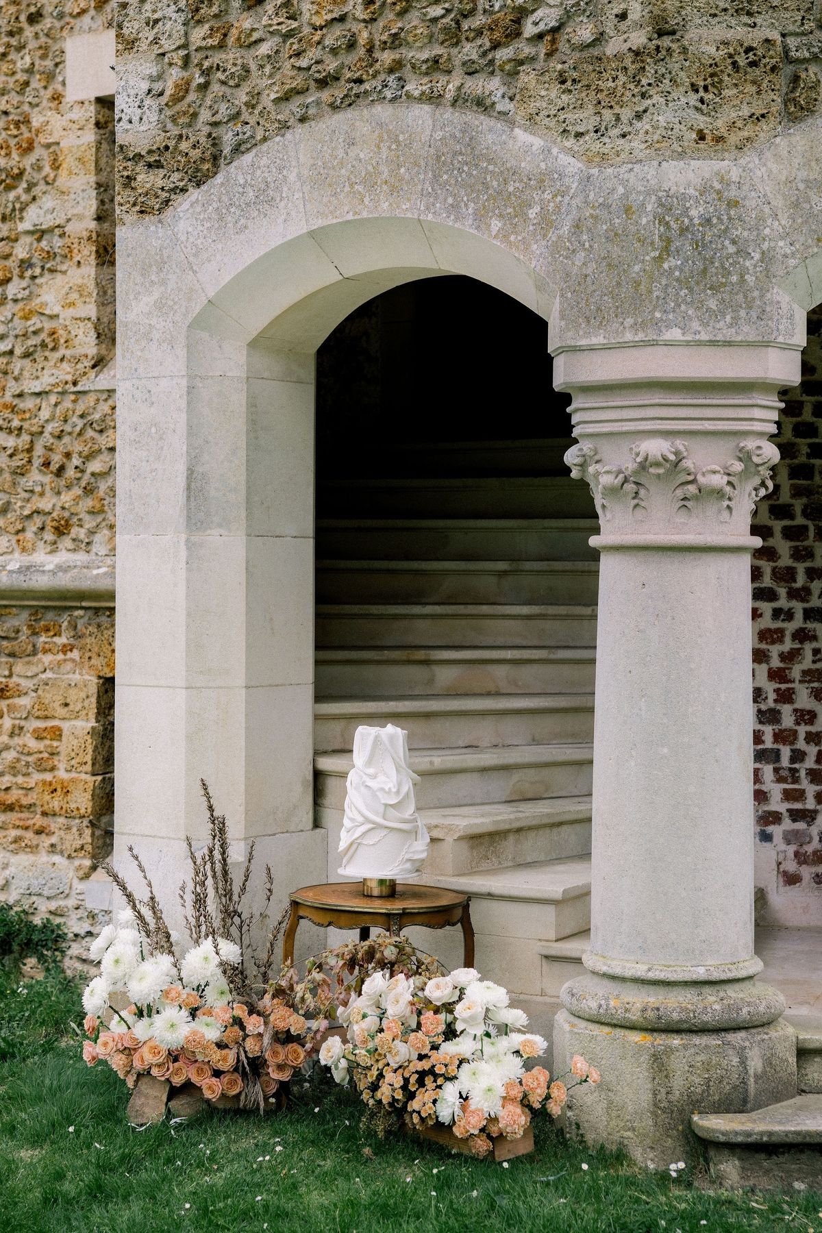 Wedding cake in arched stone entry at Château de Méridon, Île-de-France