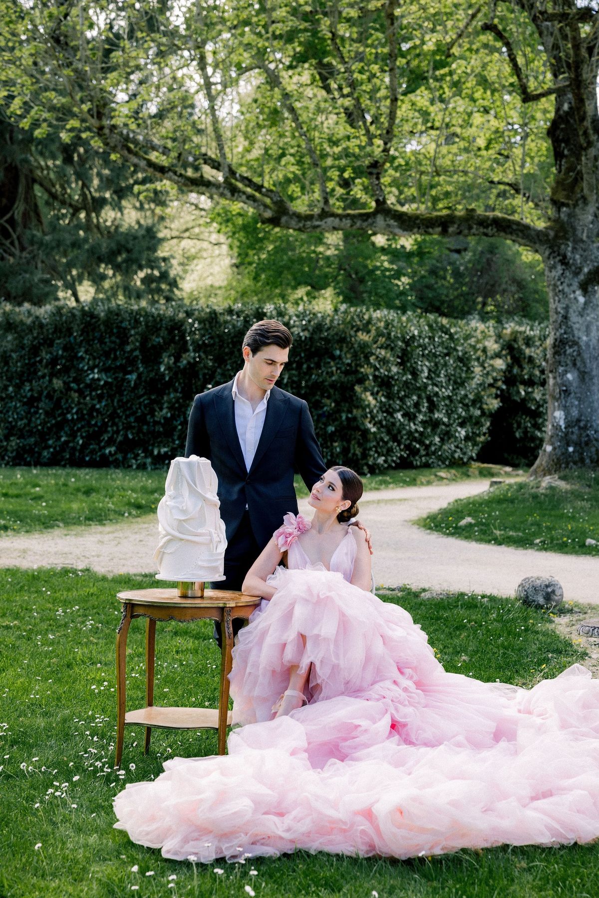 Bride and cake under tree at Château de Méridon, Île-de-France