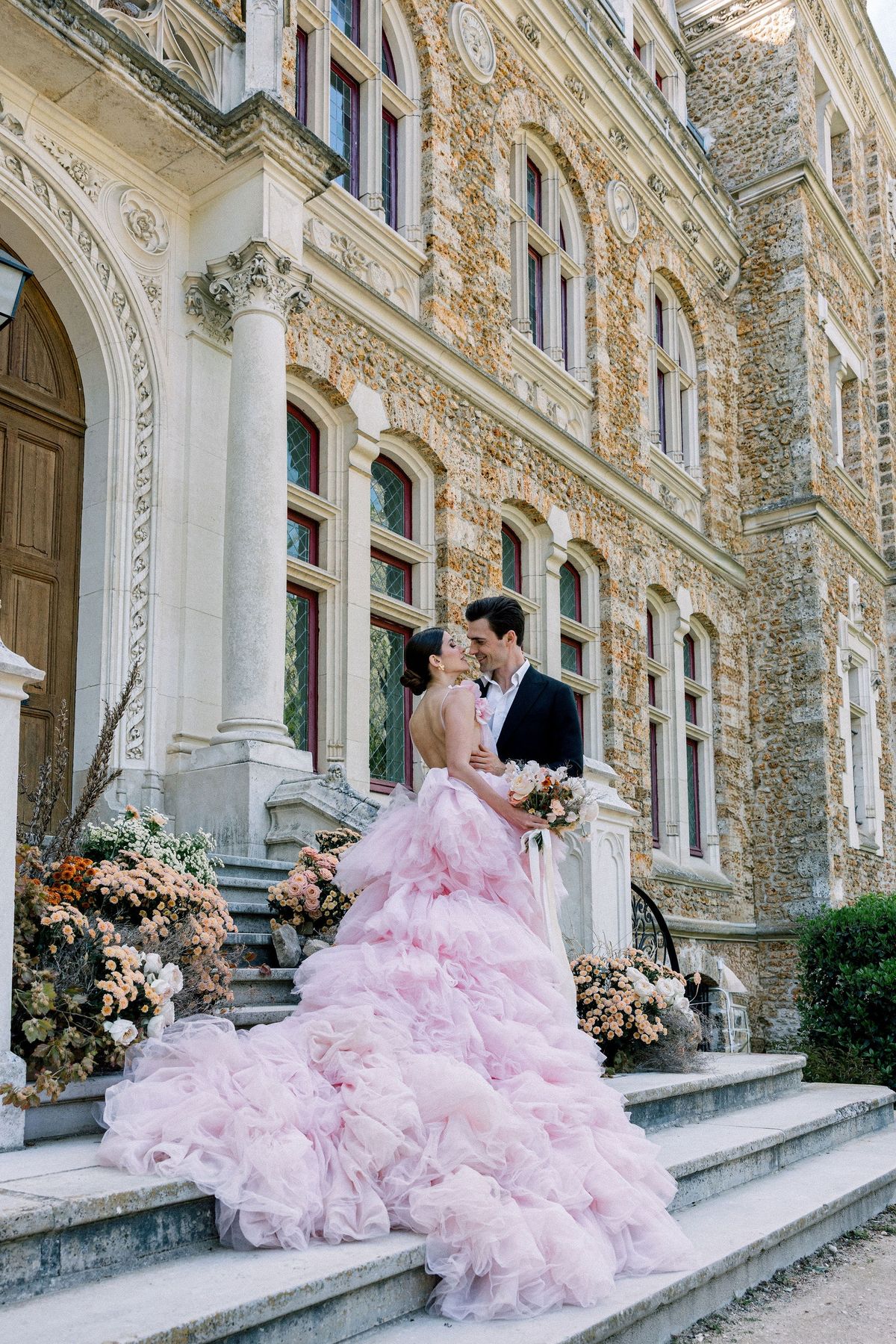 Couple on portico steps in pink gown at Château de Méridon, Île-de-France