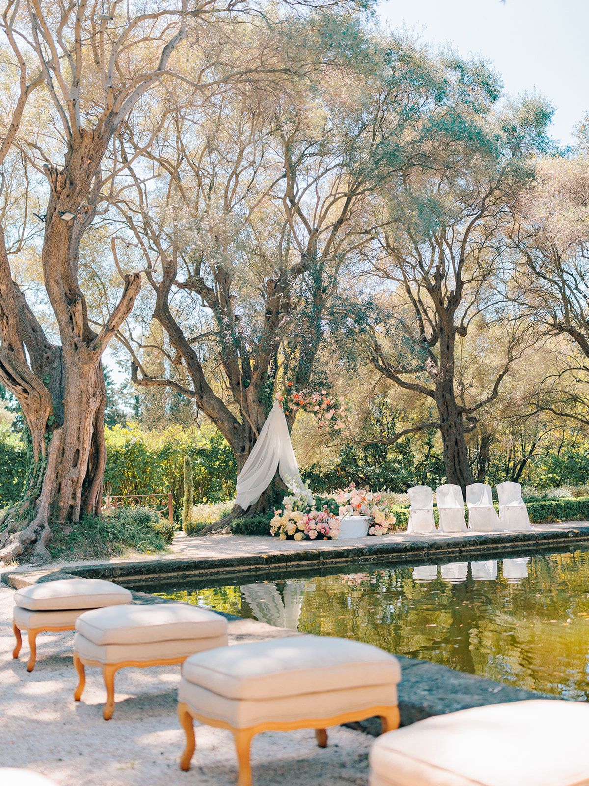 Ceremony set beside the reflecting pool with olive trees behind