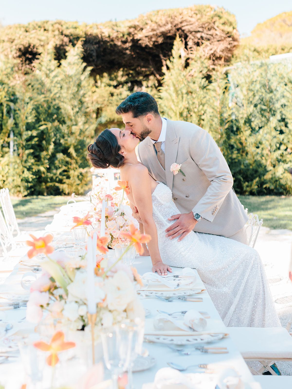 Bride and groom kissing beside the garden table setting