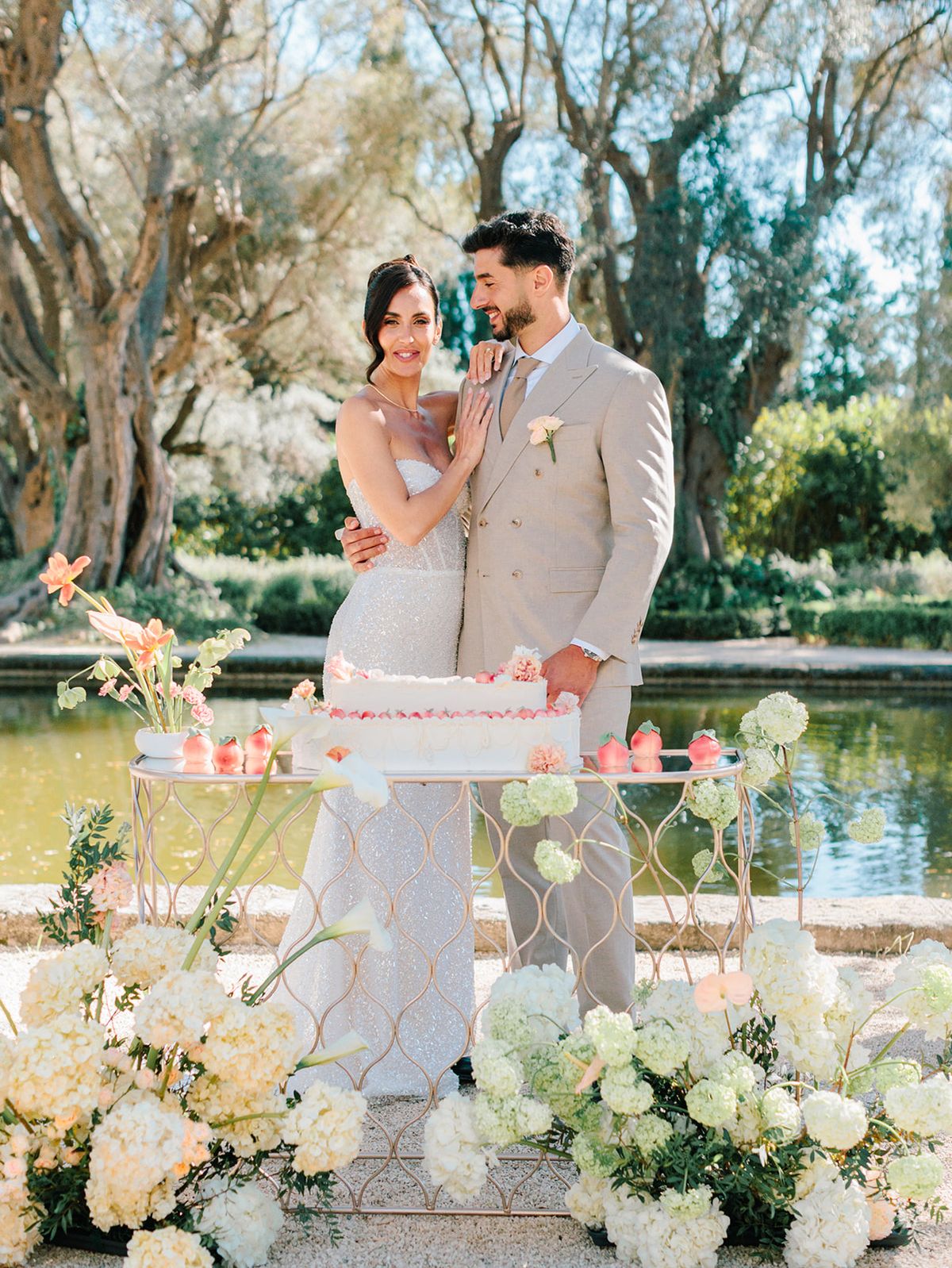 Bride and groom with their cake beside the reflecting pool