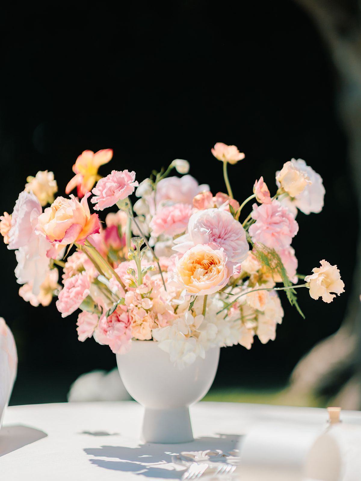 Pink and peach arrangement in a white urn