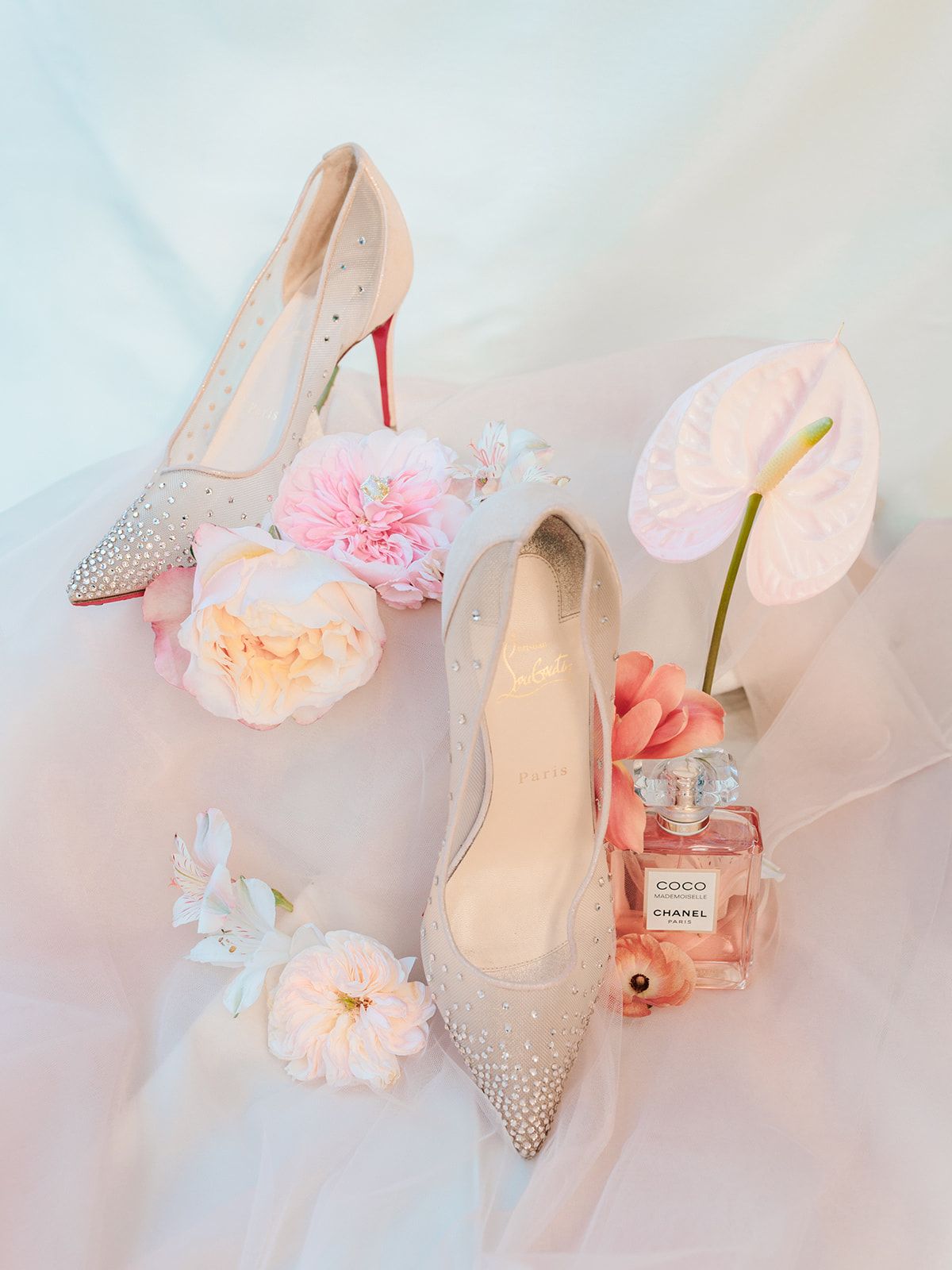 Bridal shoes, perfume and blooms arranged on tulle