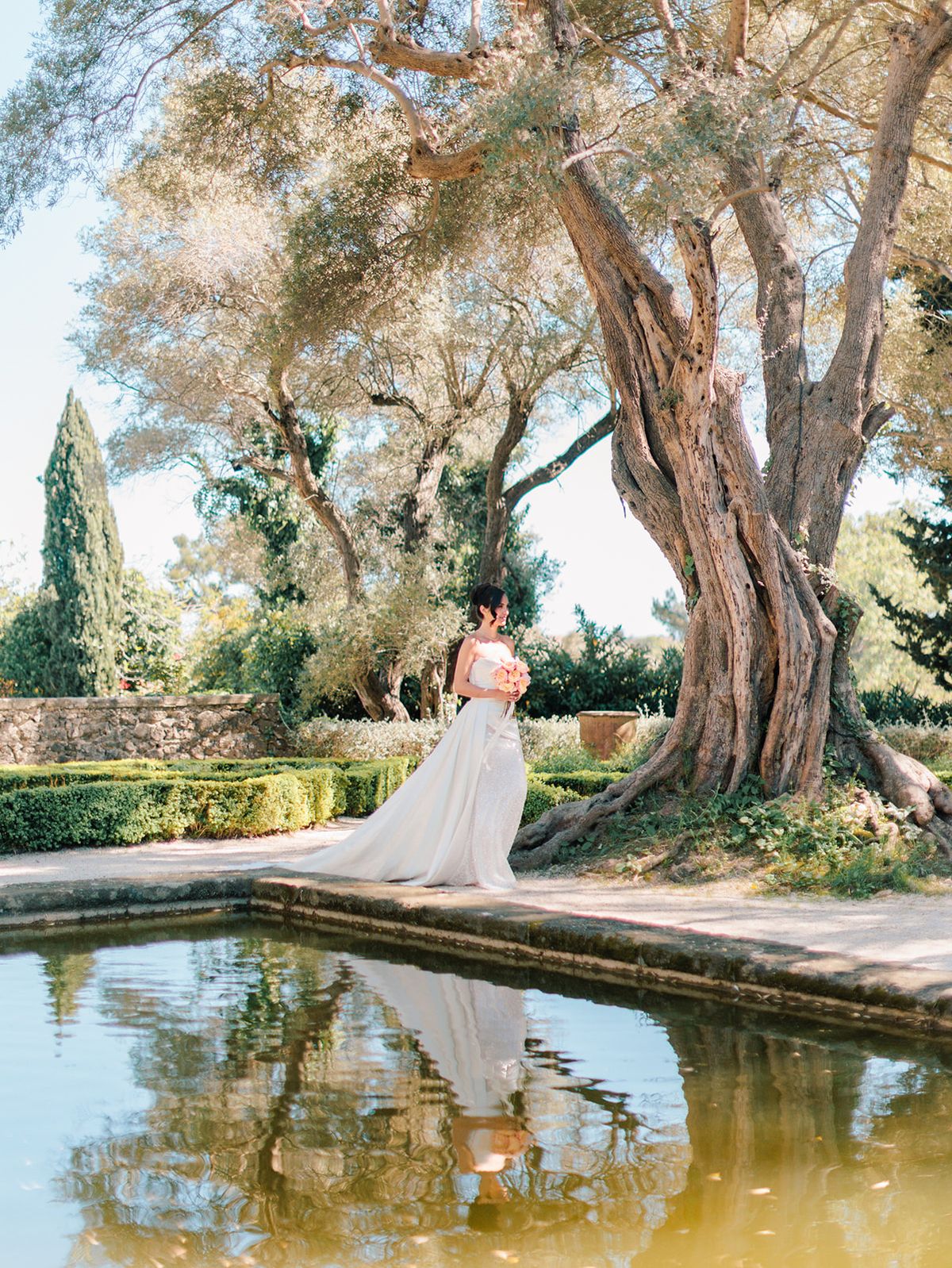 Bride beside the reflecting pool beneath the olive trees