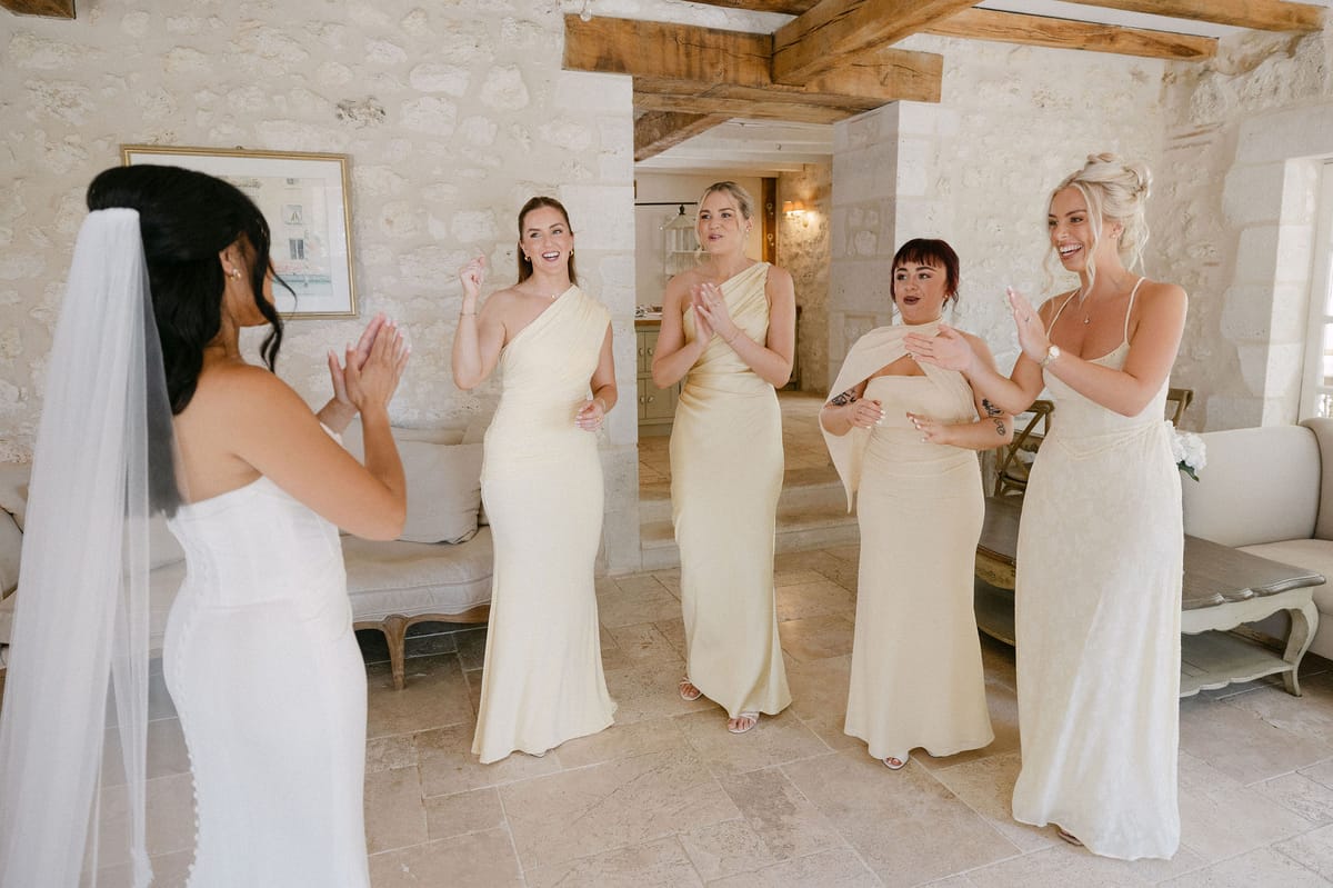 Bridesmaids in white gowns admiring the bride