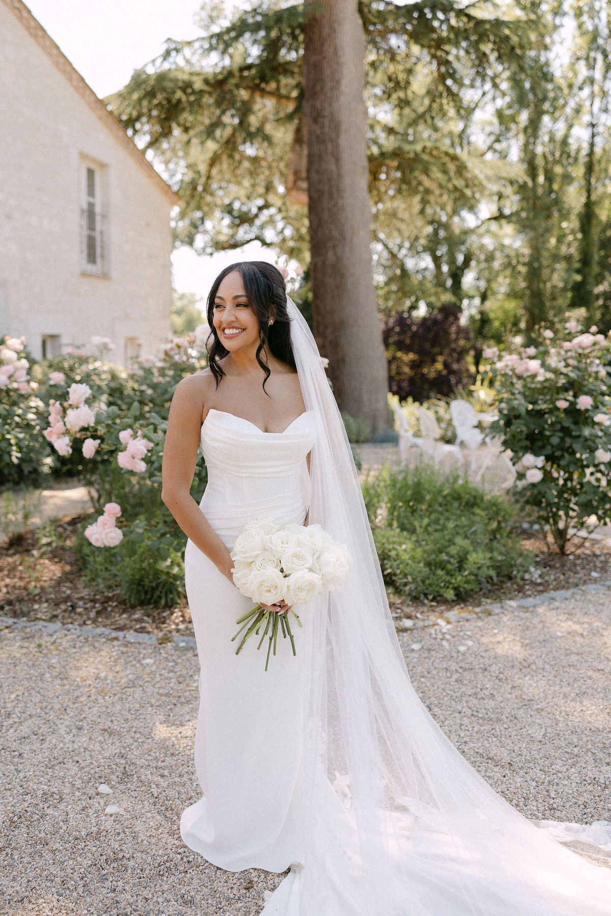 Bride with a white parasol in the rose garden