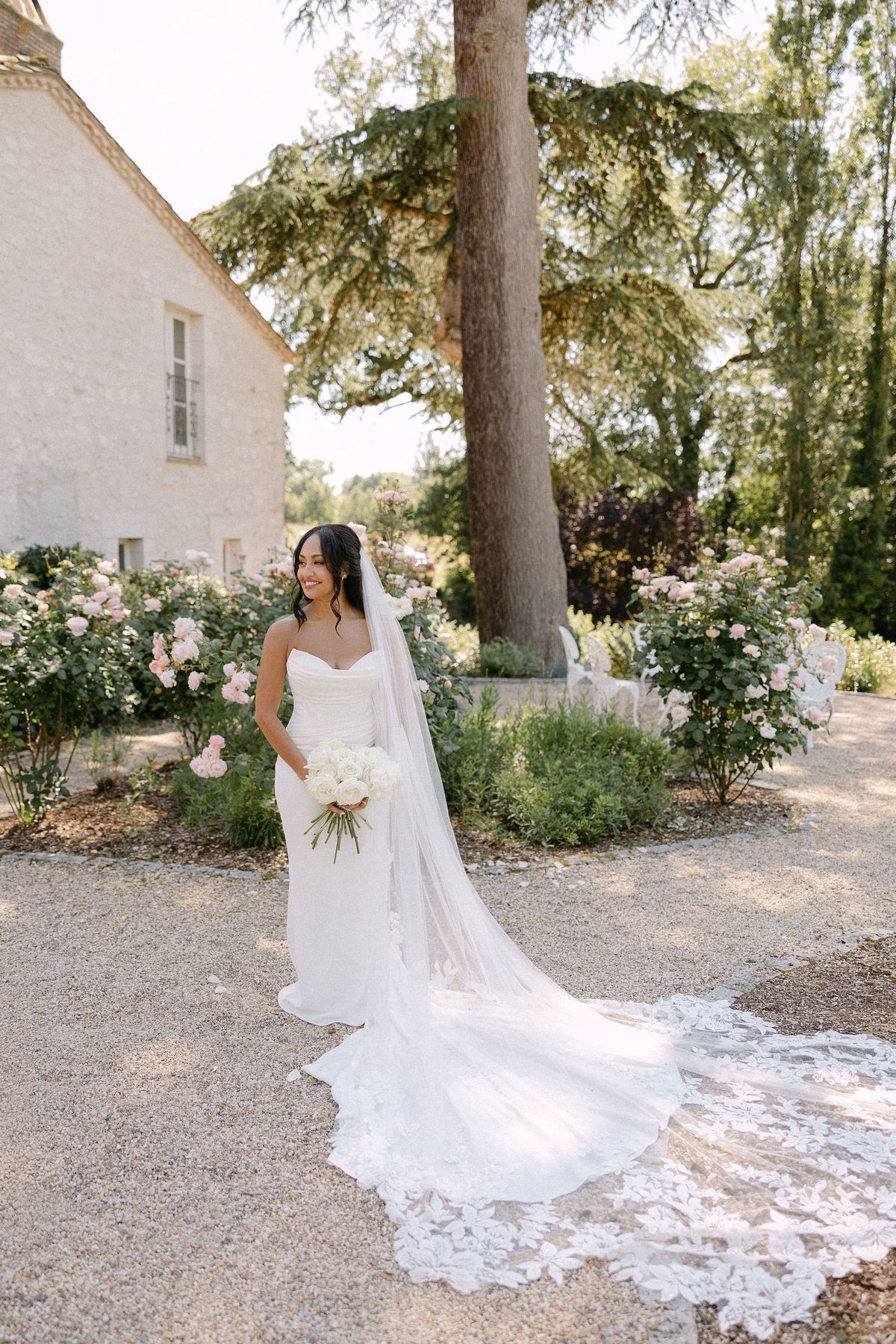 Bride walking through the rose garden in her veil