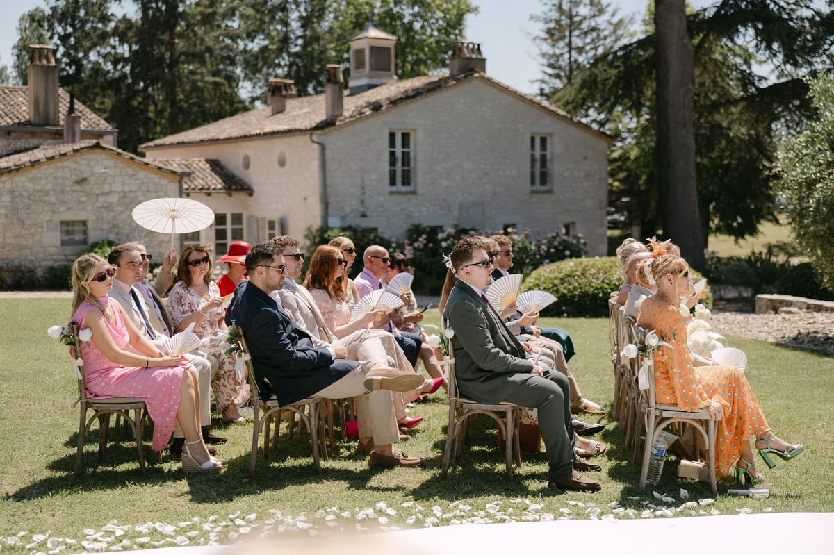 Guests fanning themselves in the summer heat during the ceremony