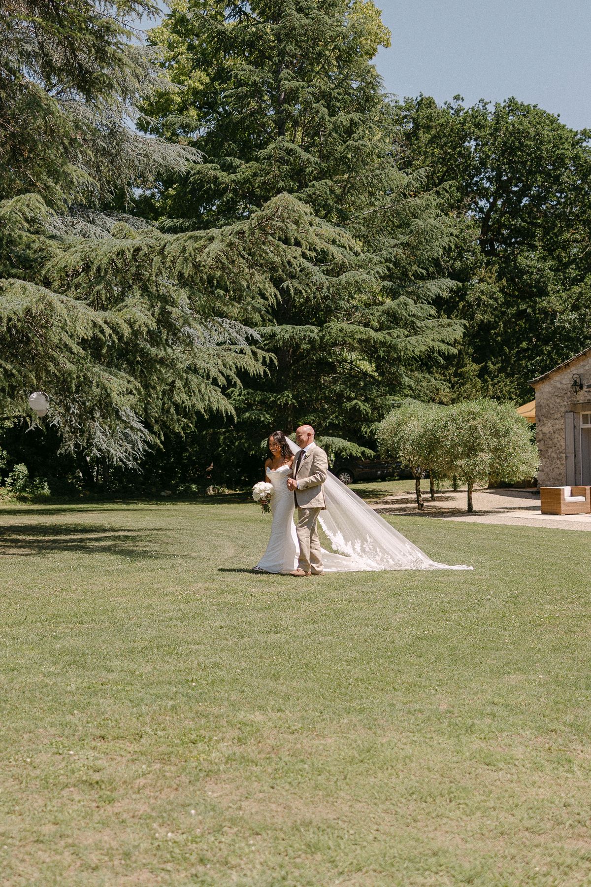 Bride and groom embracing on the lawn, château behind them