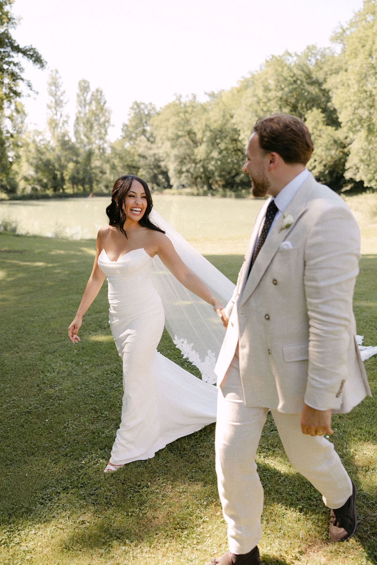 Bride and groom walking across the lawn, trees behind them