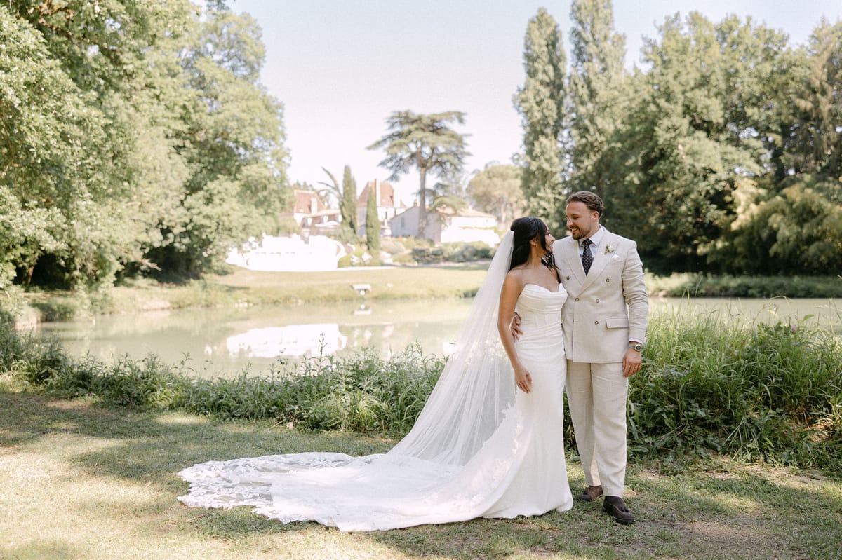 Bride and groom by the lake with the château visible across the water
