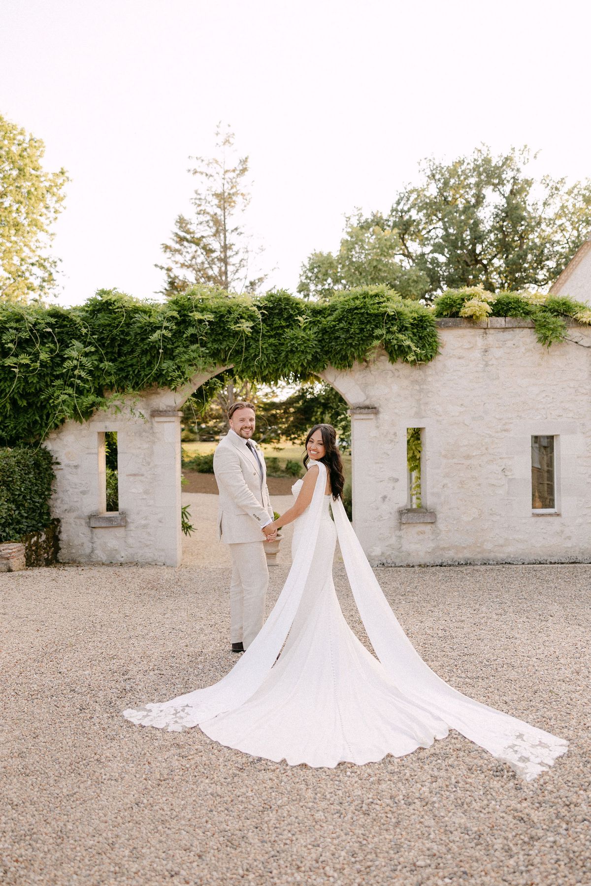 Bride and groom walking through a rose-covered archway