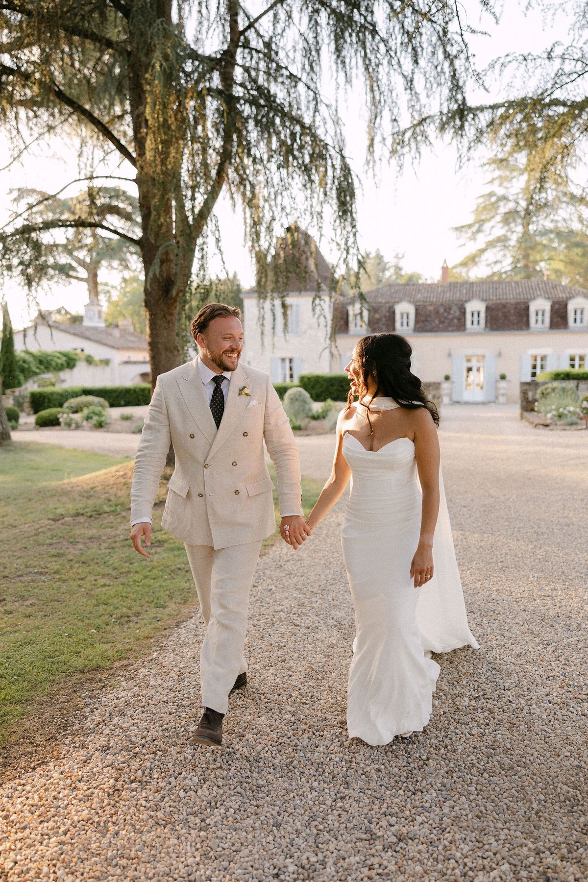 Bride and groom walking hand in hand along a path