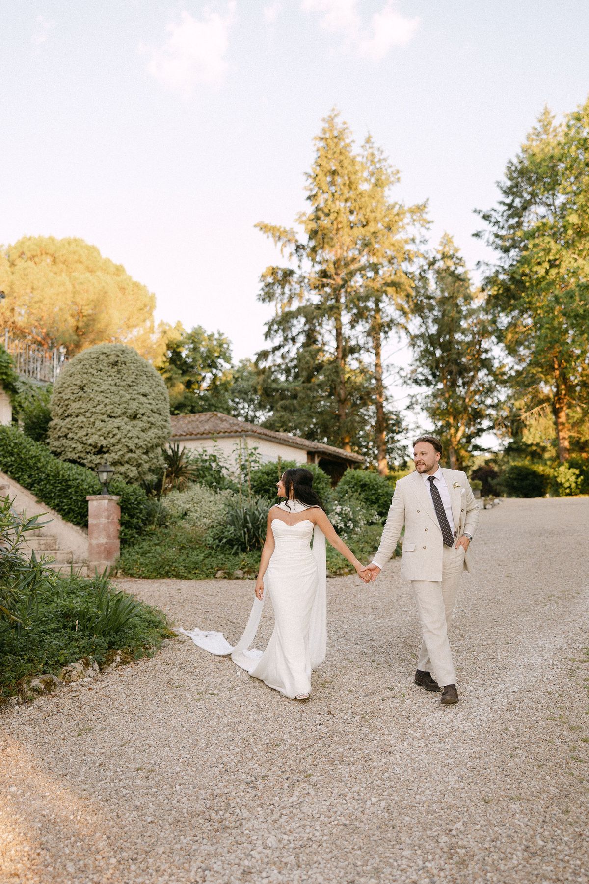 Bride and groom walking together beneath the trees