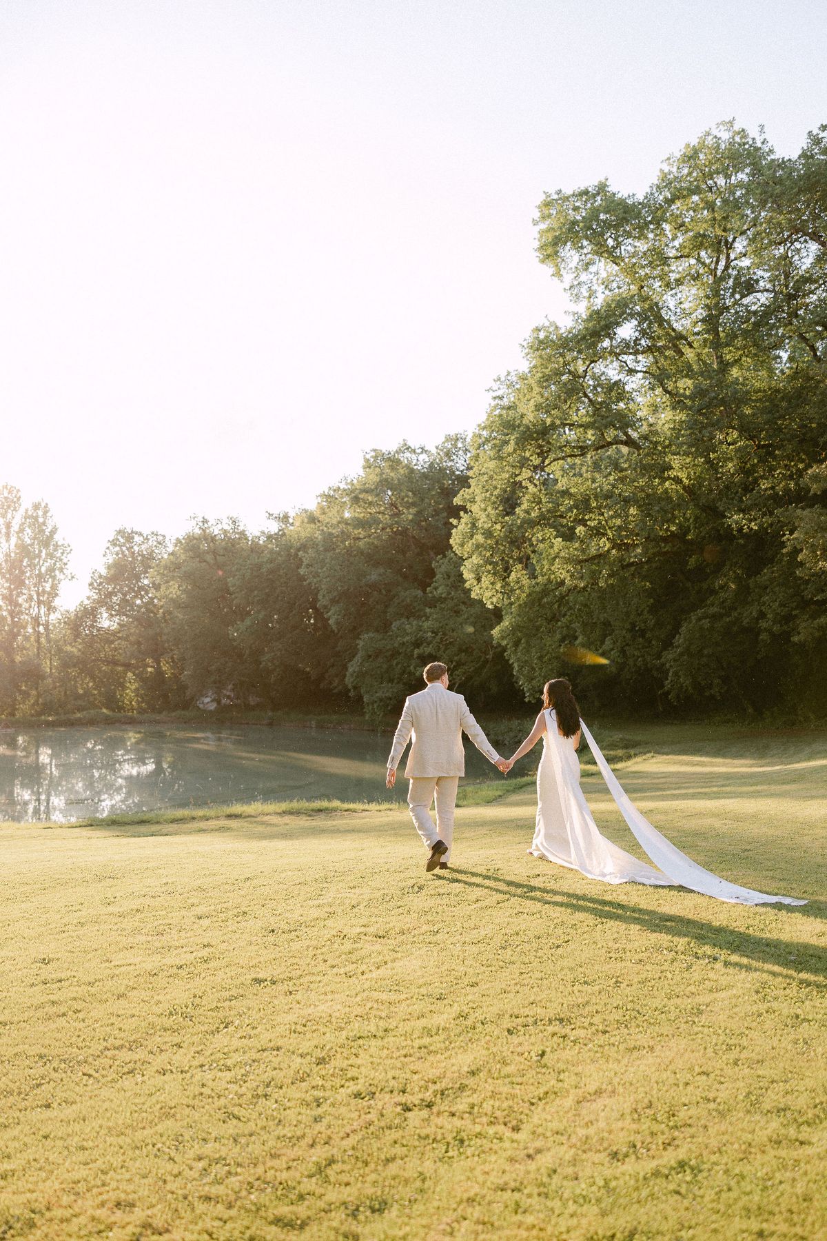 Bride and groom walking by the pond at golden hour