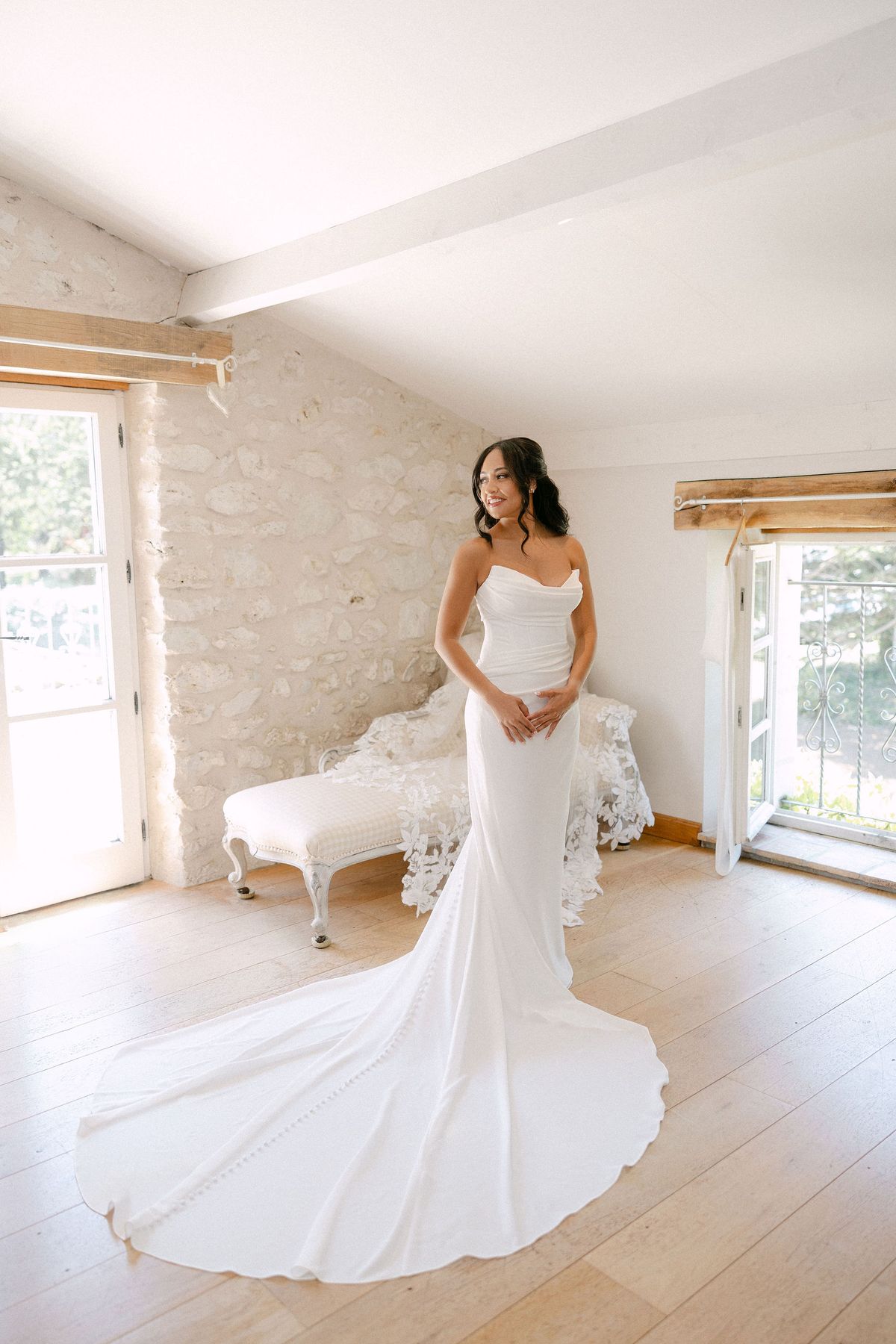 Bride standing alone in her gown by a window