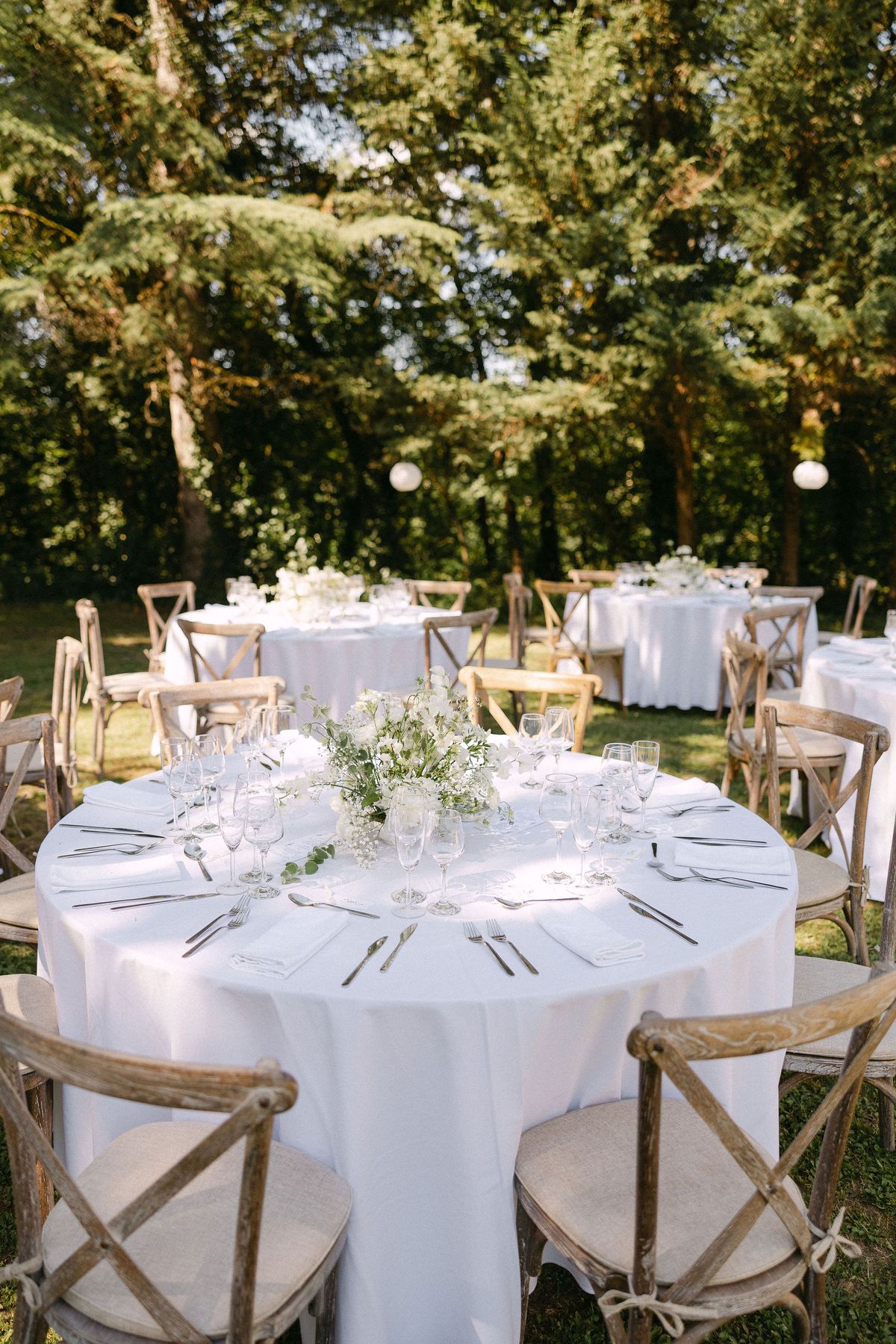 Round reception table set with white linens and greenery