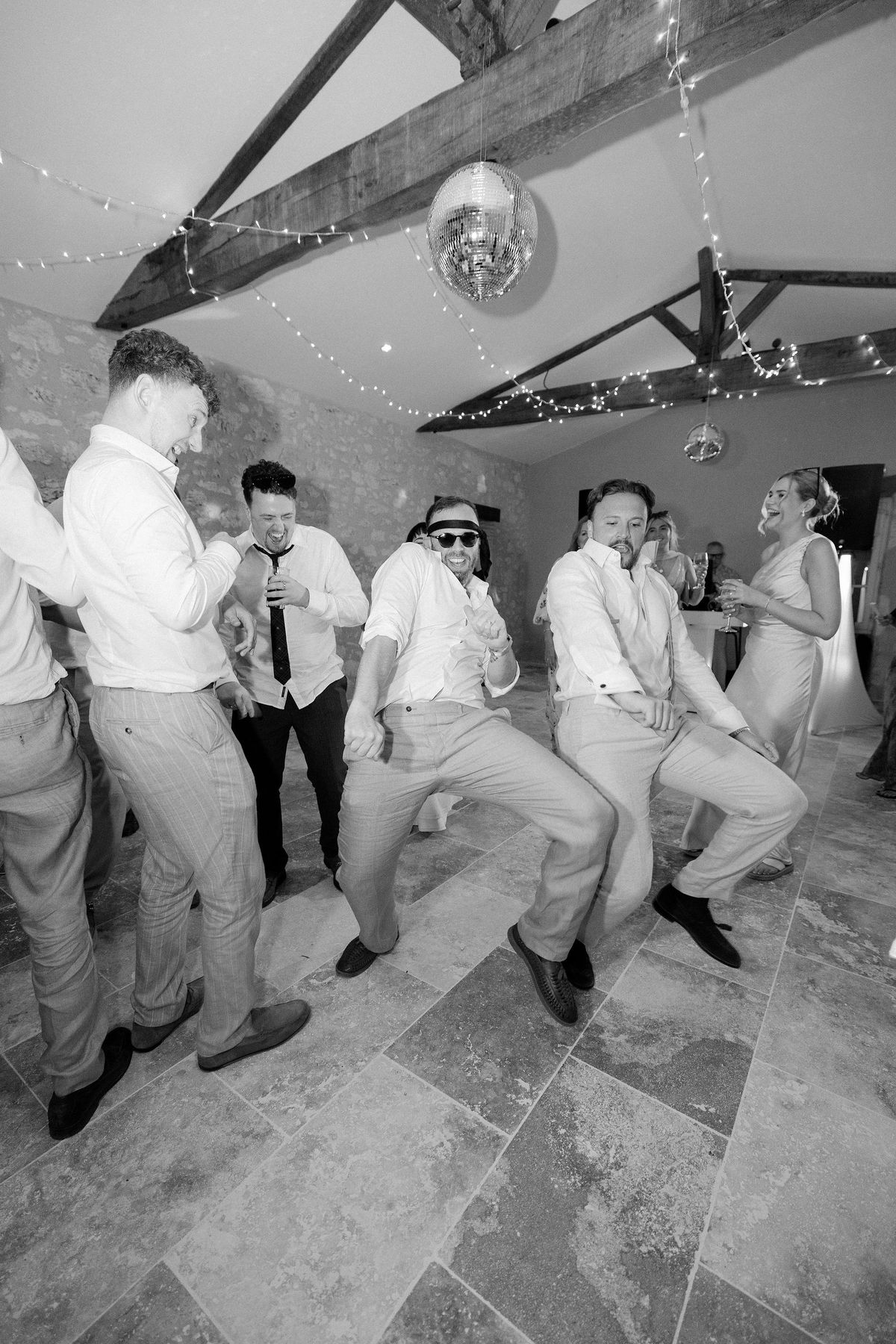 Black and white shot of groomsmen dancing at the reception