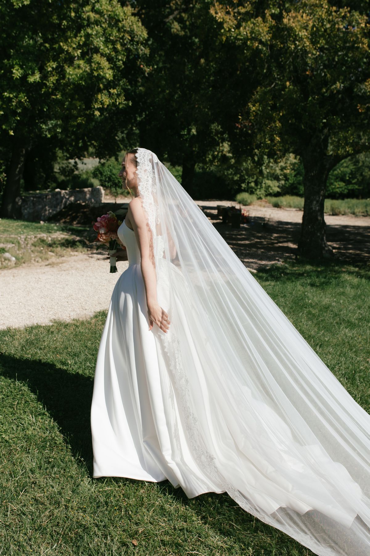 Bride in her gown and veil walking through the garden