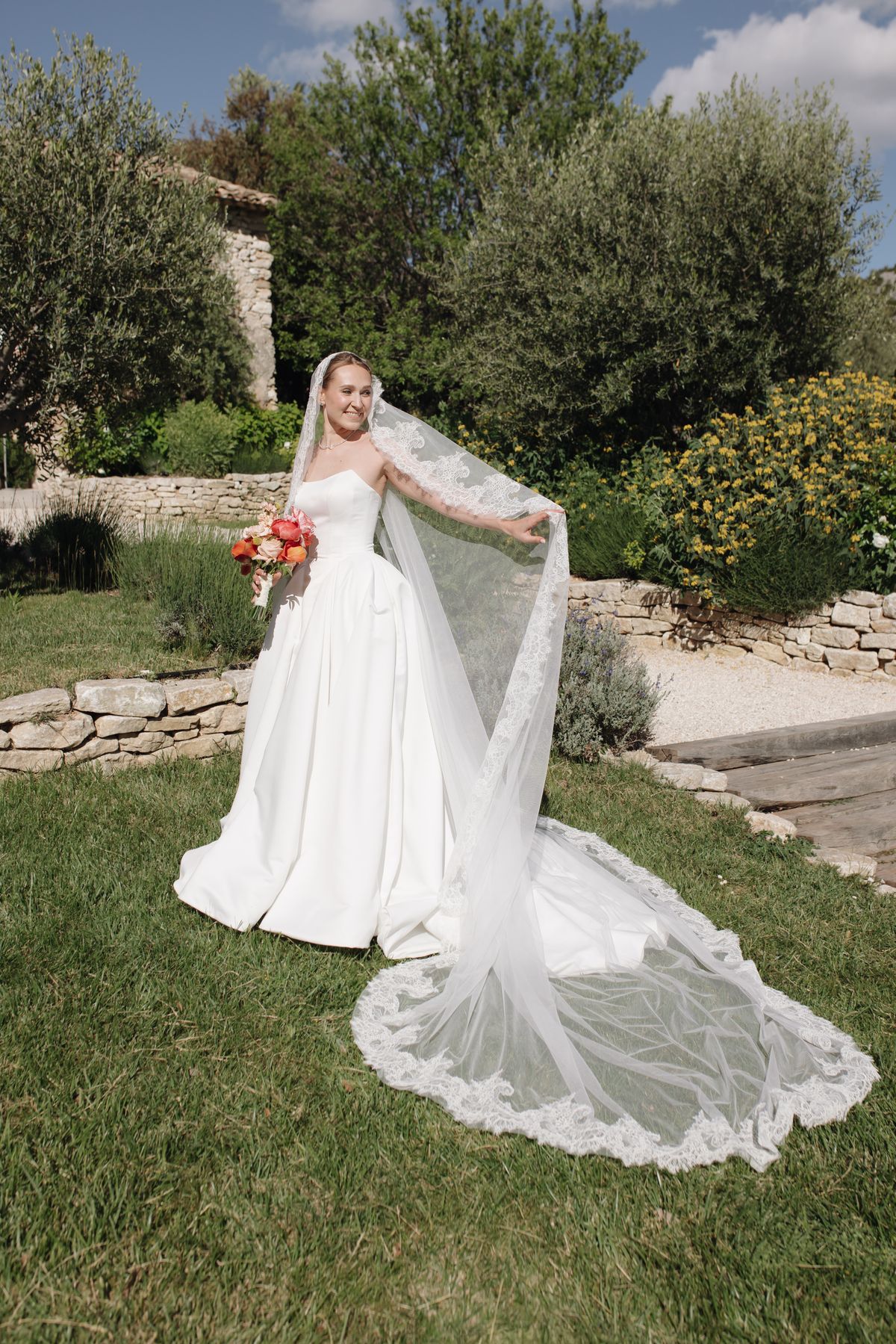 Bride holding her bouquet with her veil flowing in the wind
