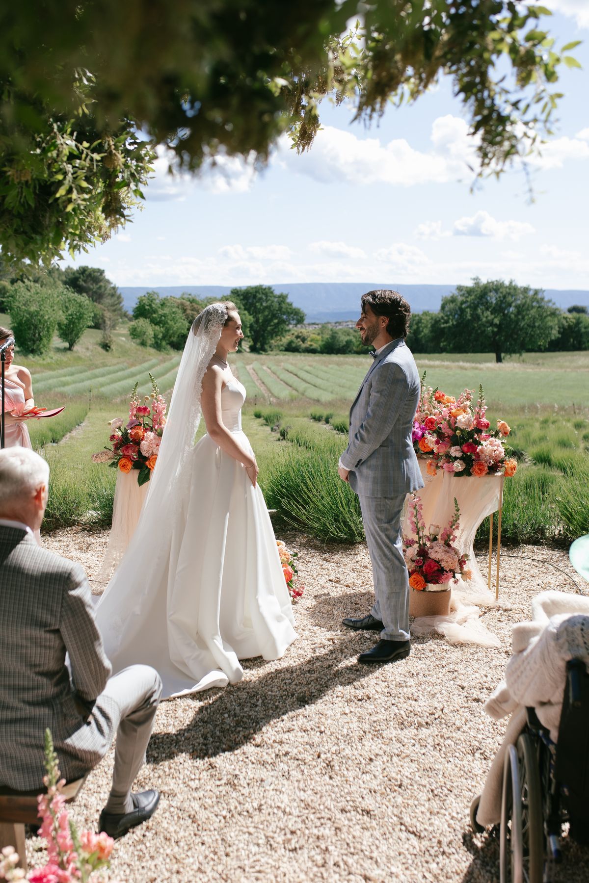 Bride and groom standing at the ceremony altar with a guest seated nearby