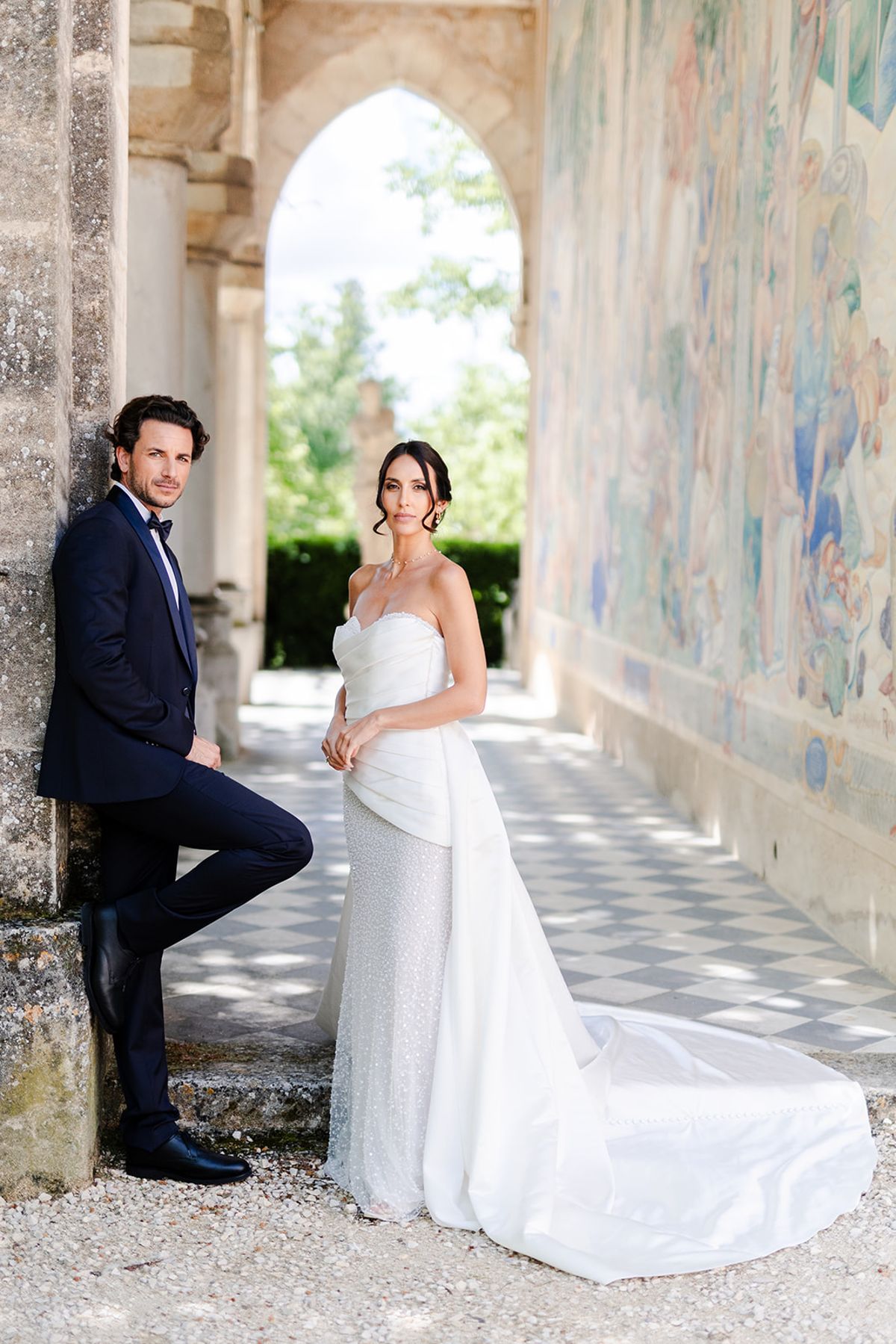 Couple in the frescoed loggia at Château de Pradines, the groom leaning on a stone column