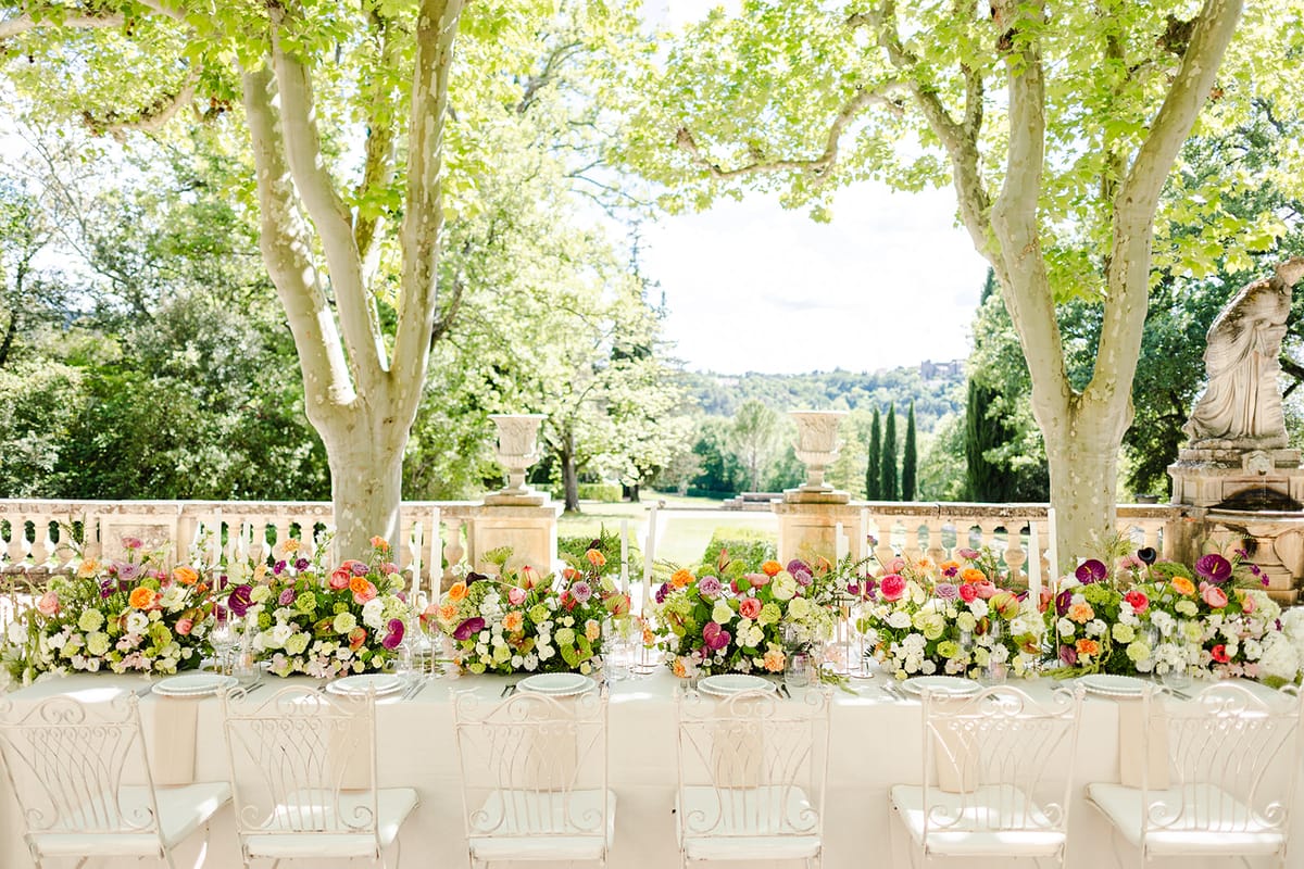 Long dinner table under the plane trees with the valley and cypress trees beyond