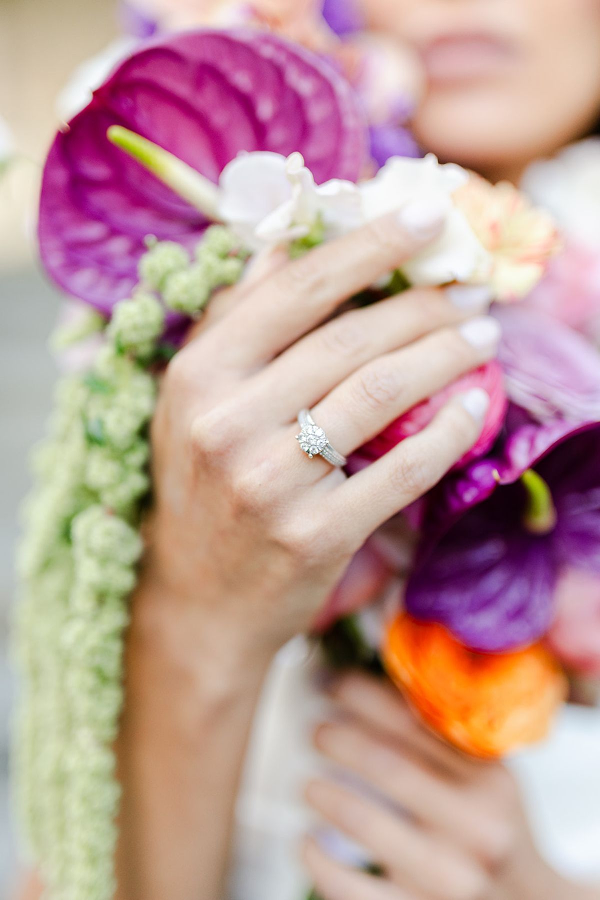 Engagement ring on the bride’s hand holding magenta anthurium and trailing amaranthus
