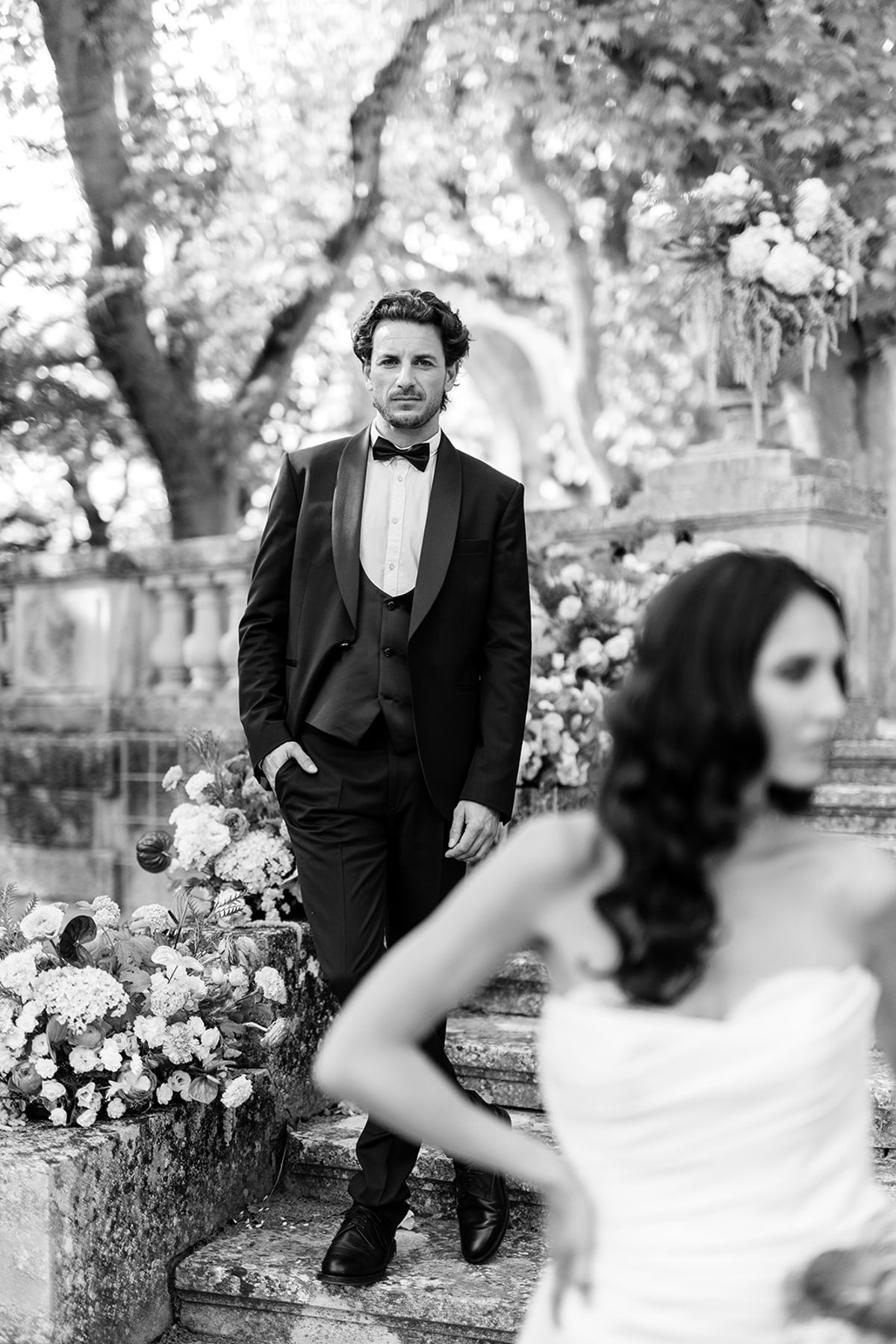 Groom on the staircase with the bride in the foreground, black and white