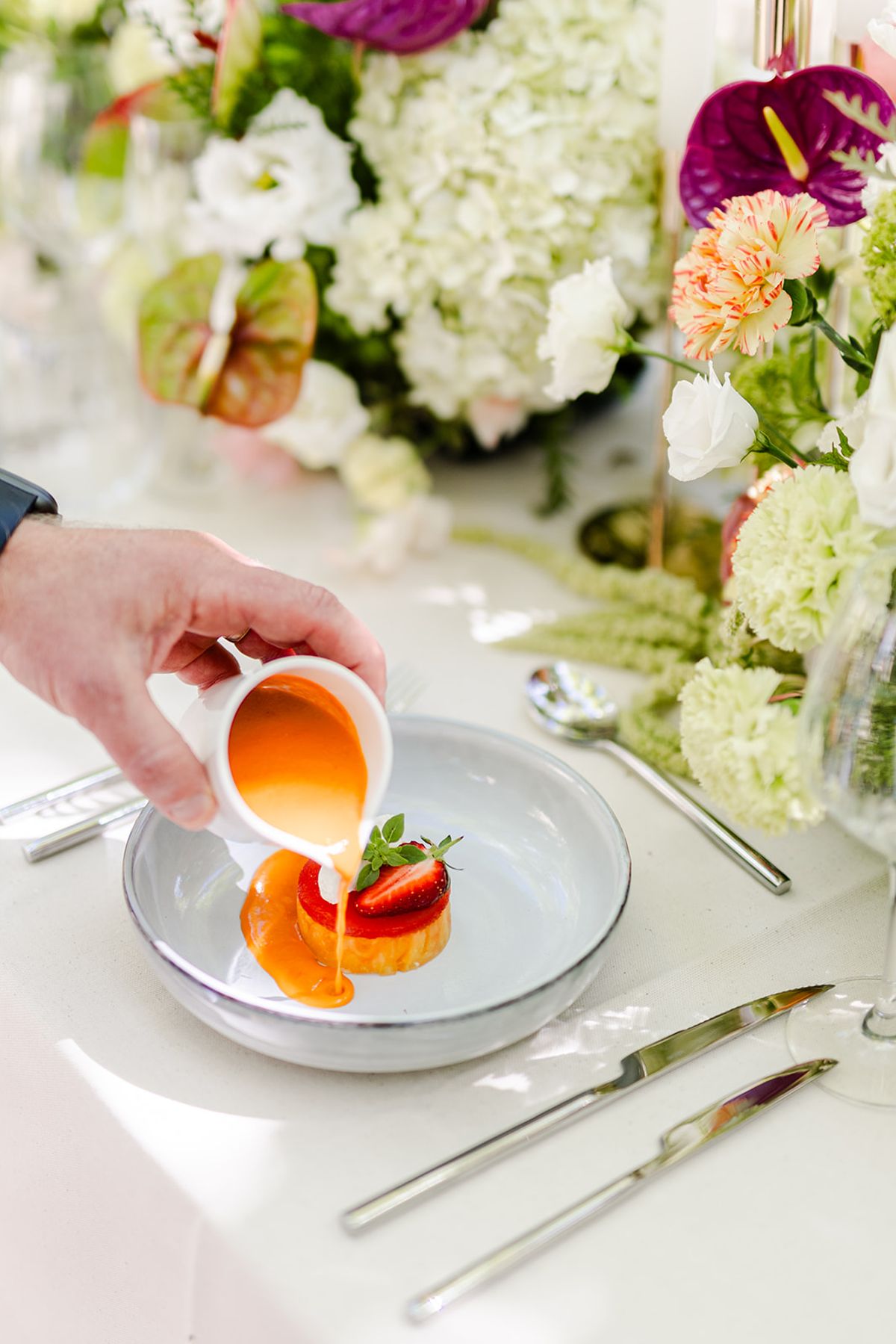 Chilled melon soup being poured at the table over strawberry and cream