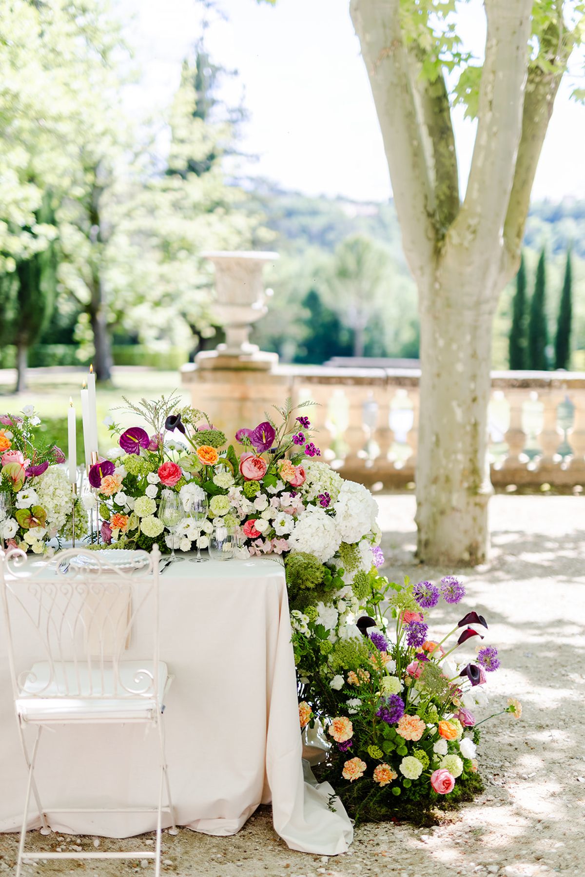 End of the dinner table with flowers banked on the gravel by the stone balustrade