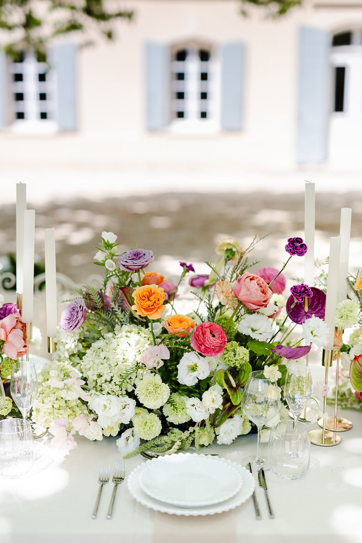 Dinner table with bright floral arrangements and taper candles in front of the château