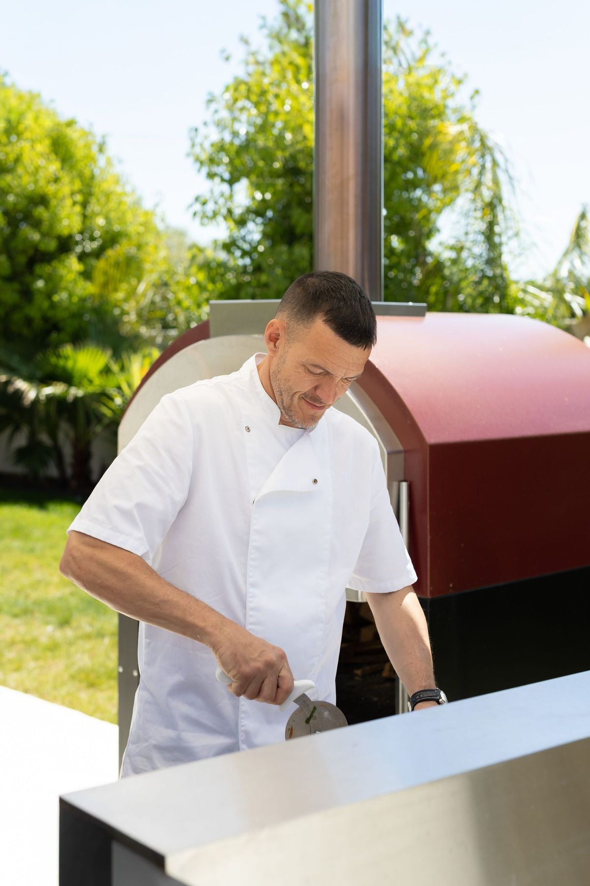 The chef cooking at the wood-fired pizza oven