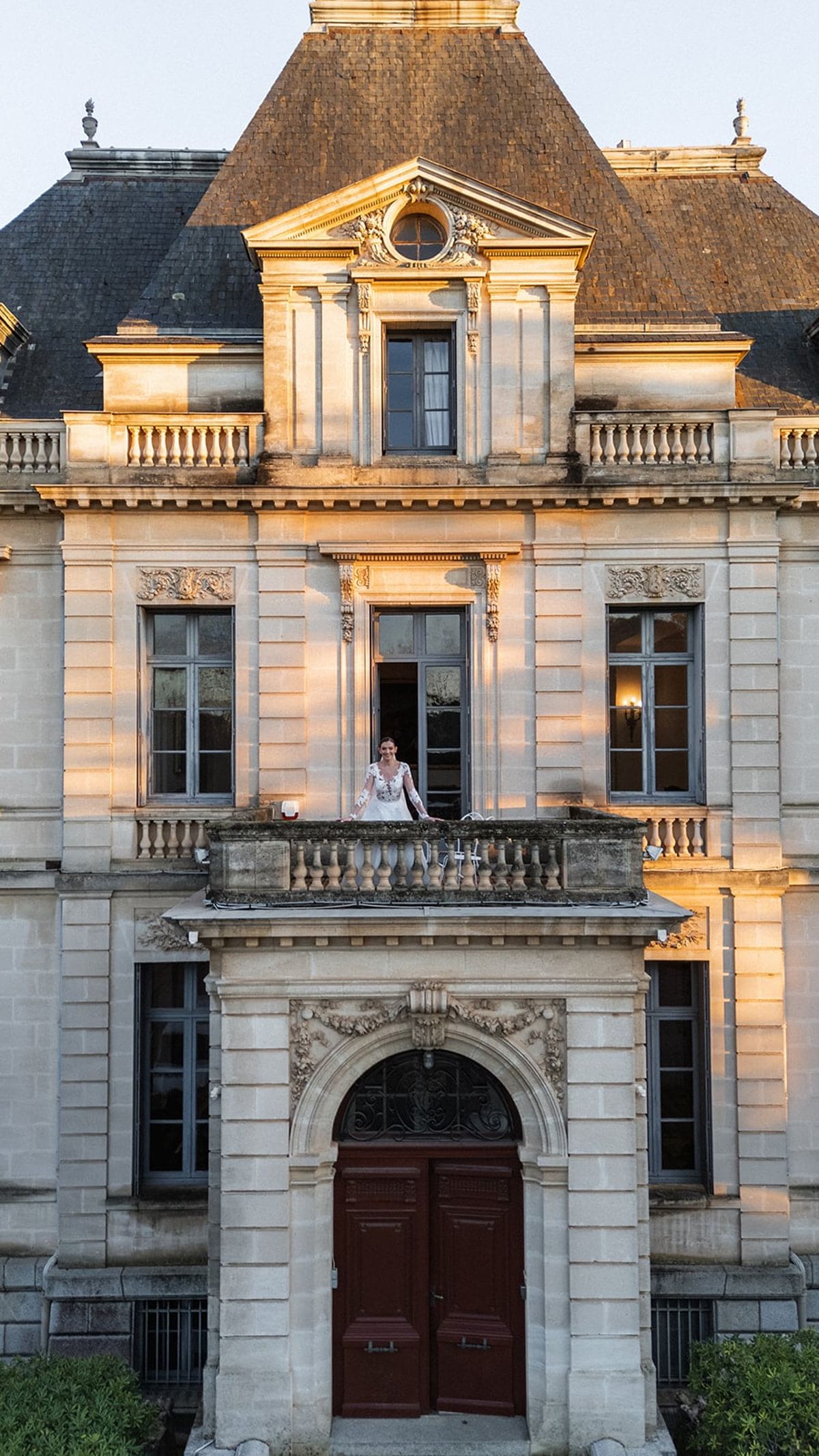 Bride on a stone-balustraded balcony of Château du Terral’s turreted facade at golden hour