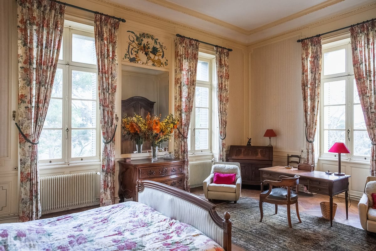 Claude bedroom suite at Château du Terral with floral curtains, antique armoire and parquet floor