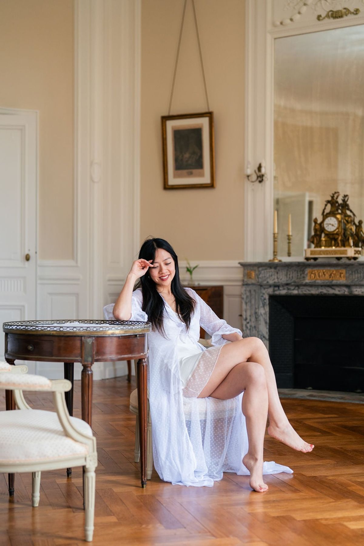 Bride seated by a round table and fireplace in a Château du Terral suite with parquet floor