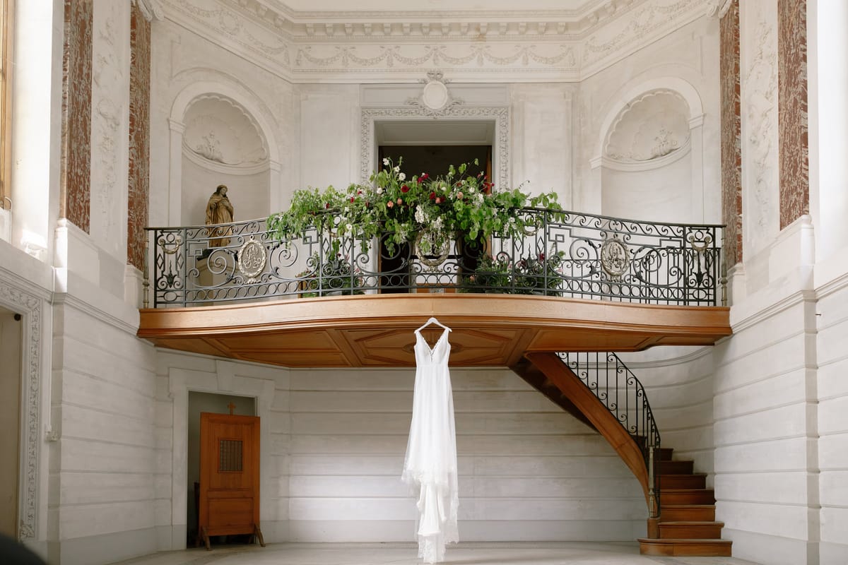 Wrought-iron balcony with floral garland overlooking the carved staircase hall at Château du Terral