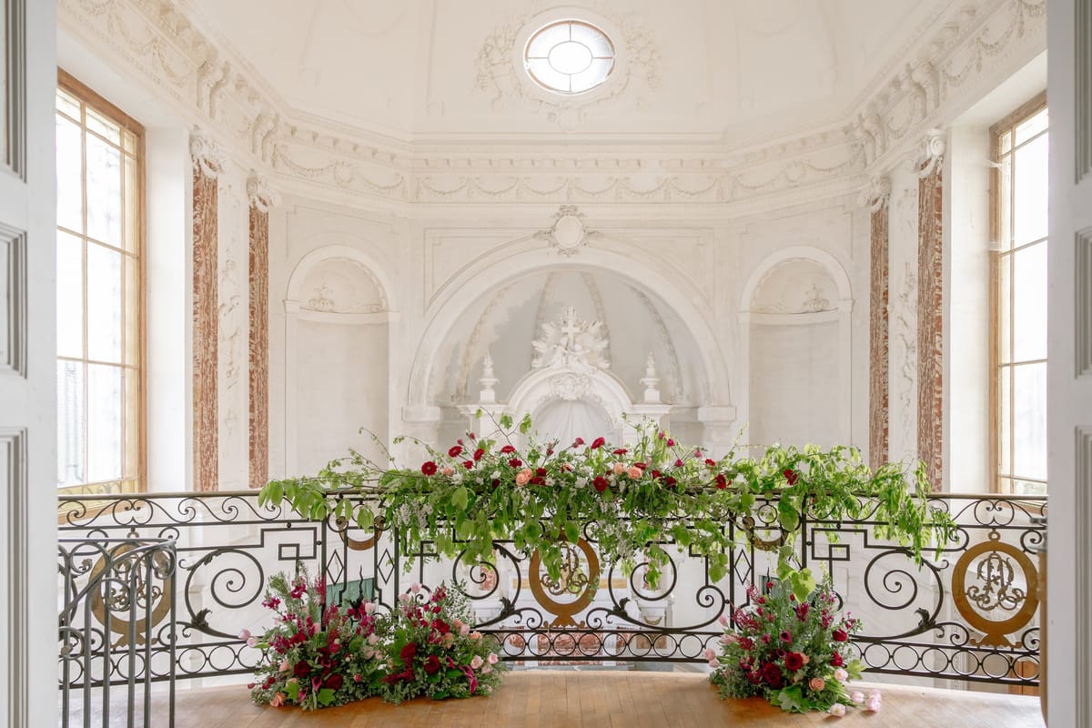 Château du Terral chapel balcony dressed with red and green florals beneath an oculus and domed ceiling