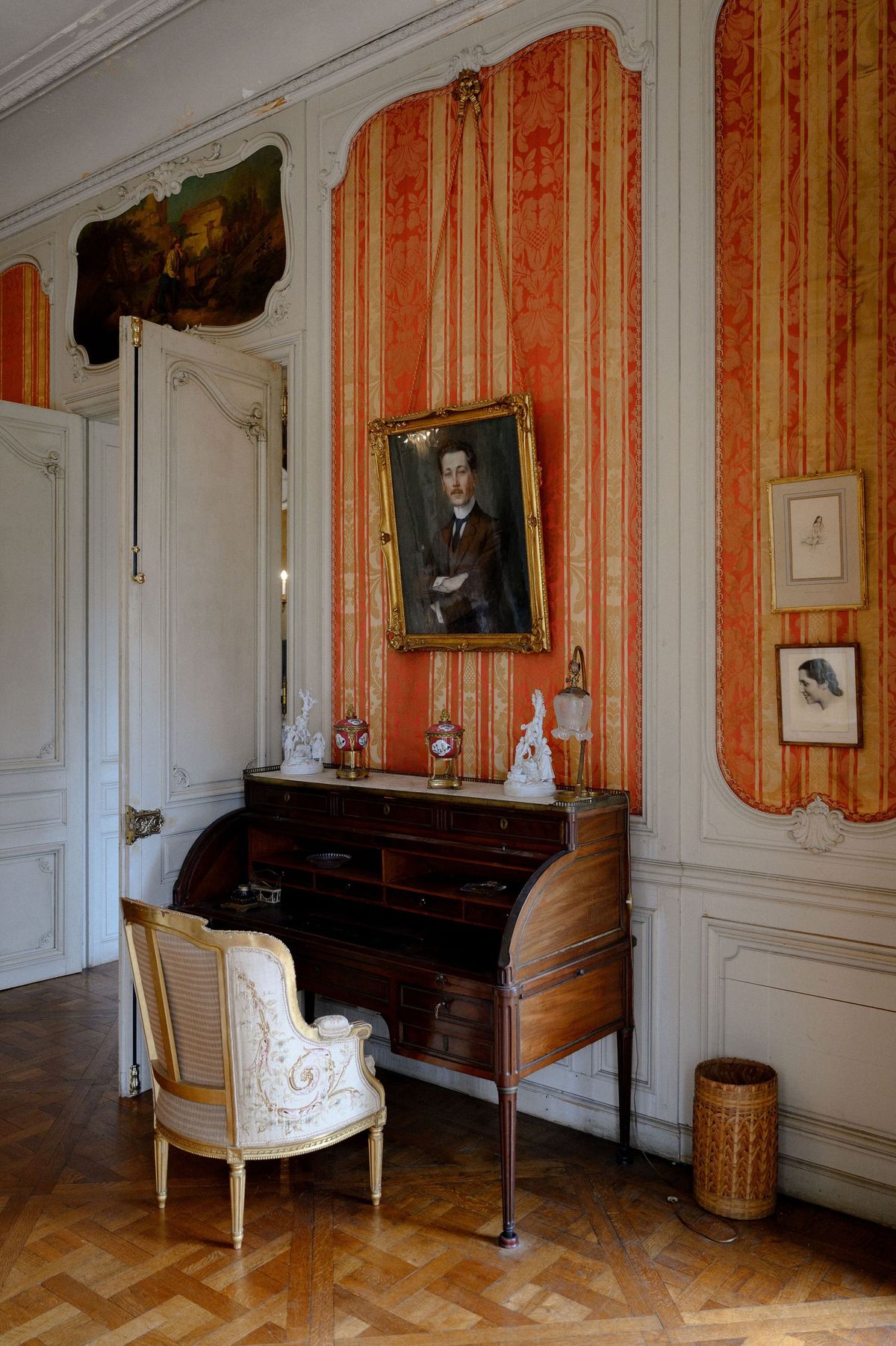 Antique cylinder desk and portrait against striped red silk walls in the grand salon at Château du Terral