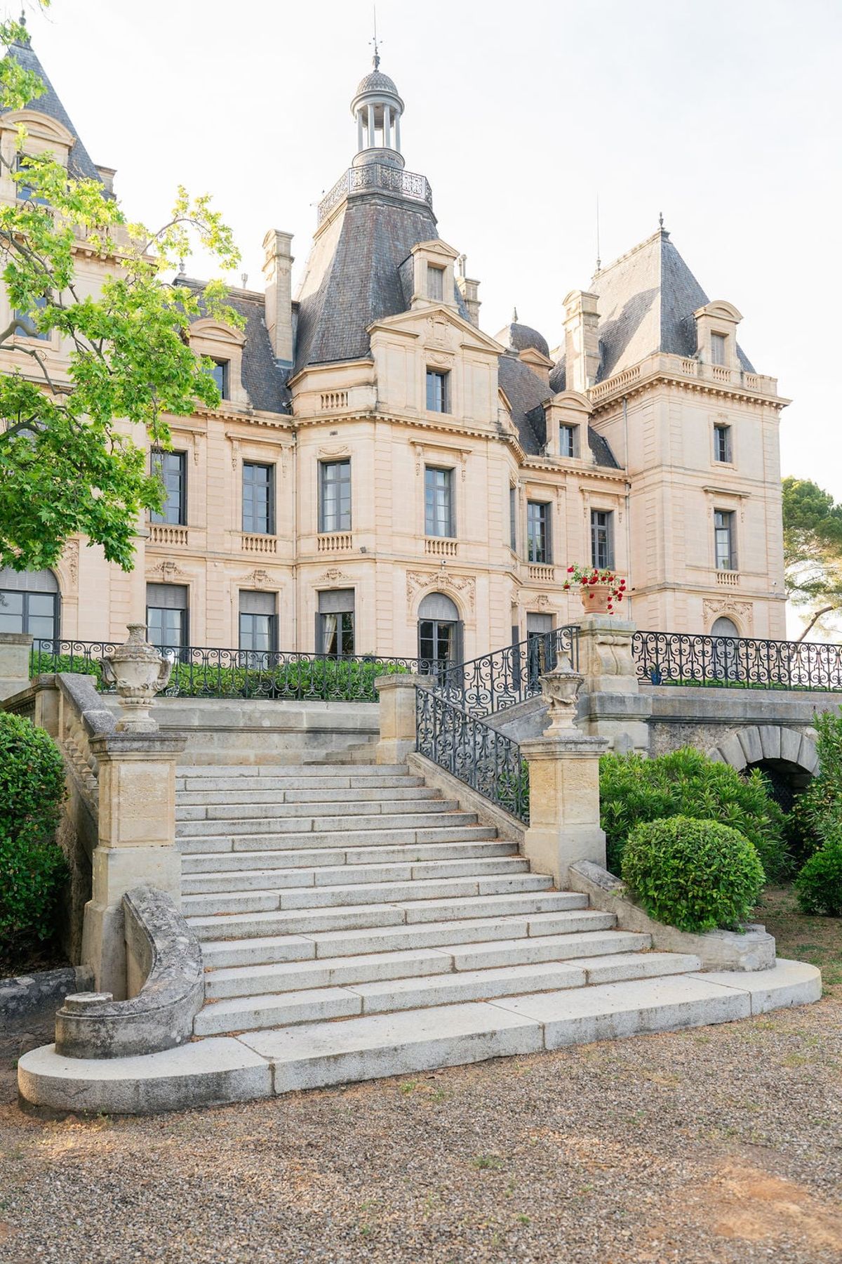 Stone steps and wrought-iron railing leading up to the turreted facade of Château du Terral
