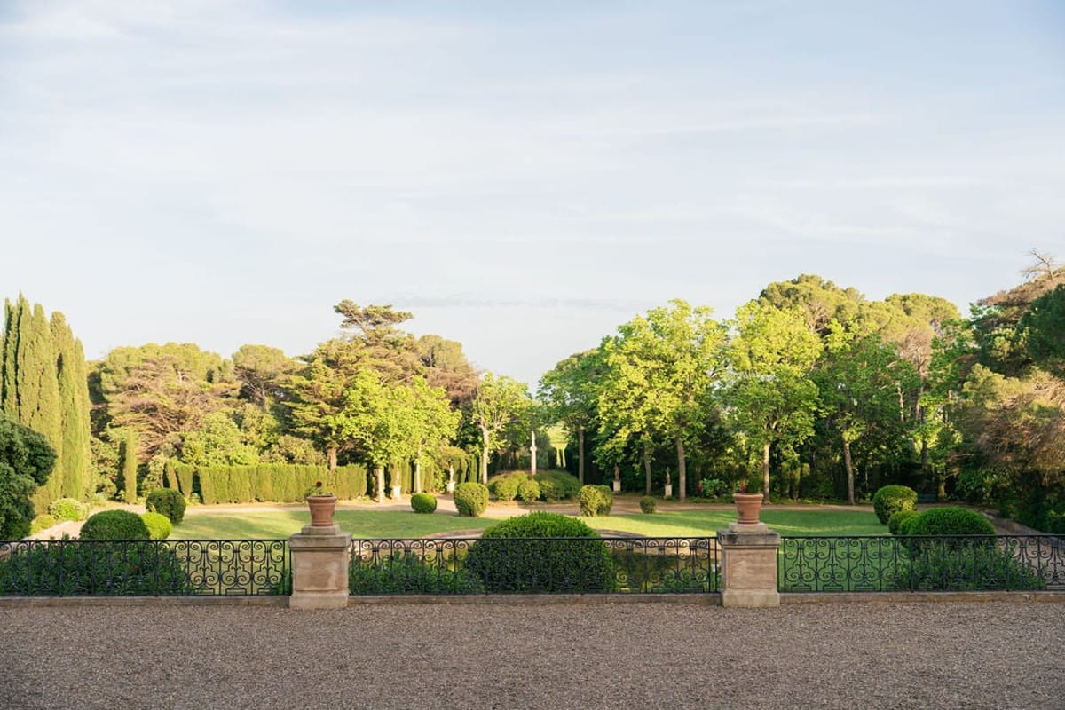 Terrace view at Château du Terral over manicured gardens, cypresses and an iron balustrade