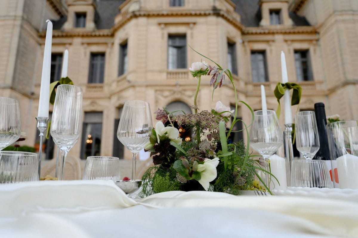 Table set with glassware and flowers before the facade of Château du Terral