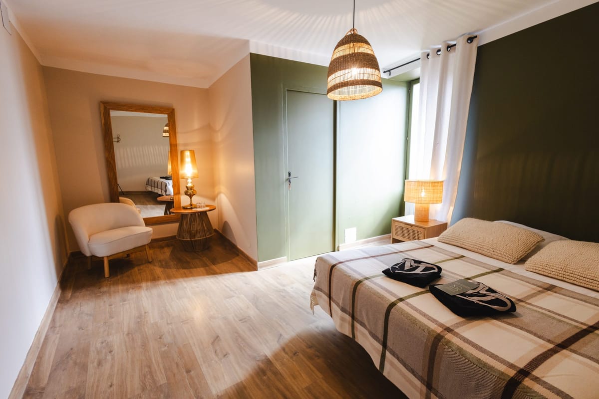 Bedroom with a green feature wall, plaid bedspread, armchair and full-length mirror